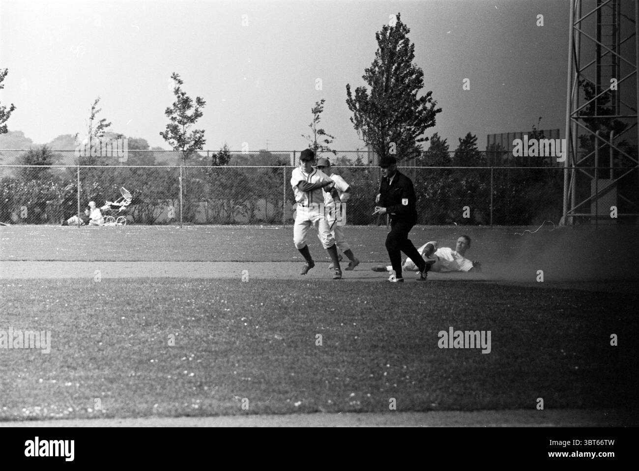 Haarlem Nicols - Belgique Anvers. Baseball, Whizgle News, Dutch Desk, pays-Bas, 1950 - 2000 le 30-05-1966. Ce sont les éléments de l'image. La scène représente un moment dynamique sur un terrain de baseball, capturant l'énergie et le mouvement du jeu. Au premier plan, deux joueurs sont en évidence, l'un sprint vers une base tandis que l'autre, vêtu d'un uniforme noir, est en position défensive, suggérant un moment critique dans le jeu. Le joueur sur la course porte un uniforme de couleur claire, qui contraste avec les tons plus sombres de l'autre étant l'arbitre. Autour de cet AC Banque D'Images
