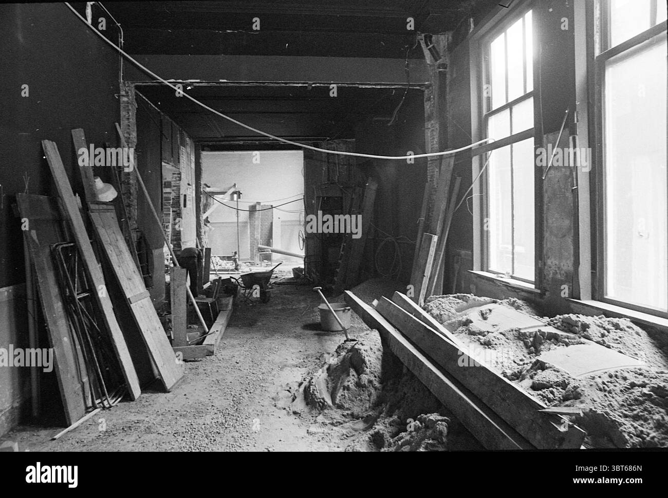 Rénovation intérieure grange de théâtre rénovations intérieures Haarlem Smedestraat pays-Bas, Whizgle News, Dutch Desk, pays-Bas, 1950 - 2000 le 22-09-1975. Ces rubriques sont illustrées dans l'image. La scène représente un espace intérieur inachevé, mettant en valeur un sentiment de construction et de rénovation en cours. Le point focal est un long couloir qui attire le regard vers l'avant, bordé de grandes fenêtres qui permettent à la lumière douce et diffuse de filtrer, éclairant les détails à l'intérieur. À gauche, il y a des piles de planches de bois et de matériaux de construction empilés de manière désordonnée, suggérant un sentiment de désarroi. Banque D'Images Rénovation intérieure grange de théâtre rénovations intérieures Haarlem Smedestraat pays-Bas, Whizgle News, Dutch Desk, pays-Bas, 1950 - 2000 le 22-09-1975. Ces rubriques sont illustrées dans l'image. La scène représente un espace intérieur inachevé, mettant en valeur un sentiment de construction et de rénovation en cours. Le point focal est un long couloir qui attire le regard vers l'avant, bordé de grandes fenêtres qui permettent à la lumière douce et diffuse de filtrer, éclairant les détails à l'intérieur. À gauche, il y a des piles de planches de bois et de matériaux de construction empilés de manière désordonnée, suggérant un sentiment de désarroi. Banque D'Images