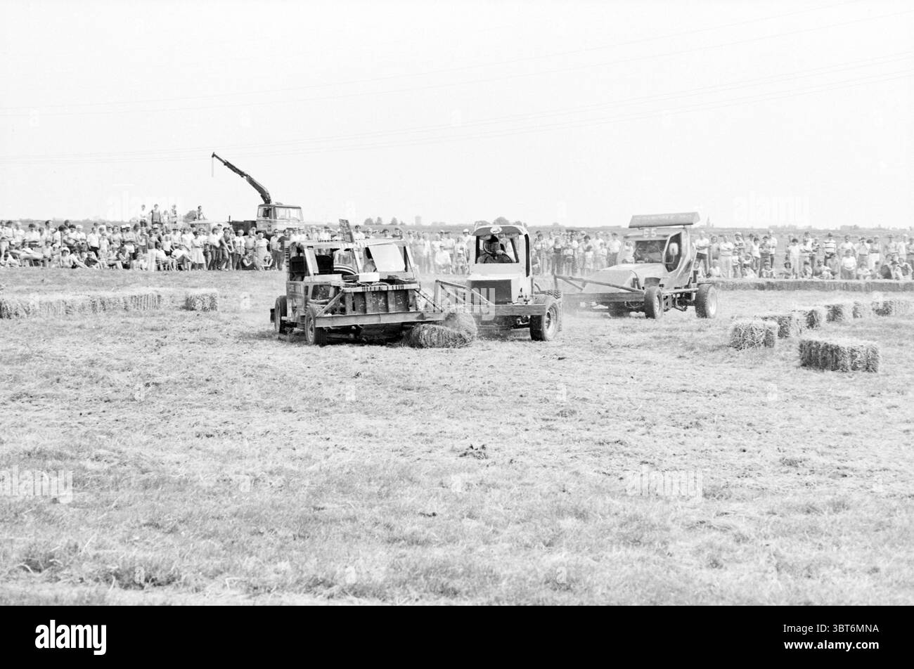 Smash Up derby car course on Field, Whizgle News, Dutch Desk, pays-Bas, 1950 - 2000 sur 07-1983. Voici les rubriques de l'image. Dans un grand champ ouvert, la scène est dominée par plusieurs machines agricoles engagées dans une compétition animée. Deux machines distinctes travaillent visiblement à la création de balles de foin ; l'une est positionnée au premier plan tandis que l'autre est légèrement en arrière et sur le côté. Chaque machine présente un design industriel robuste, avec une combinaison de couleurs discrètes, principalement des nuances de gris, et des notes de peinture altérée. L'équipement contraste nettement avec l'or Banque D'Images