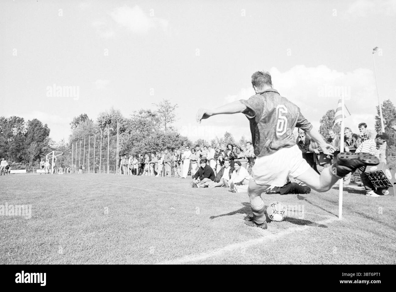 John de Wolf remporte une coupe de Nieuw-Vennep Nieuw-Vennep, Whizgle News, Dutch Desk, pays-Bas, 1950 - 2000 le 14-05-1993. L'image contient ces rubriques. La scène capture un moment dynamique lors d'un match de football. Au premier plan, un joueur portant un maillot foncé, marqué du numéro 6, est prêt à prendre un corner. Sa posture est athlétique et concentrée, un pied ancré sur l'herbe tandis qu'il se prépare à frapper la balle, qui repose à quelques centimètres du drapeau d'angle. Le fond est rempli de spectateurs, une foule de personnes diverses assis et debout. Ils sont engagés, certains debout Banque D'Images