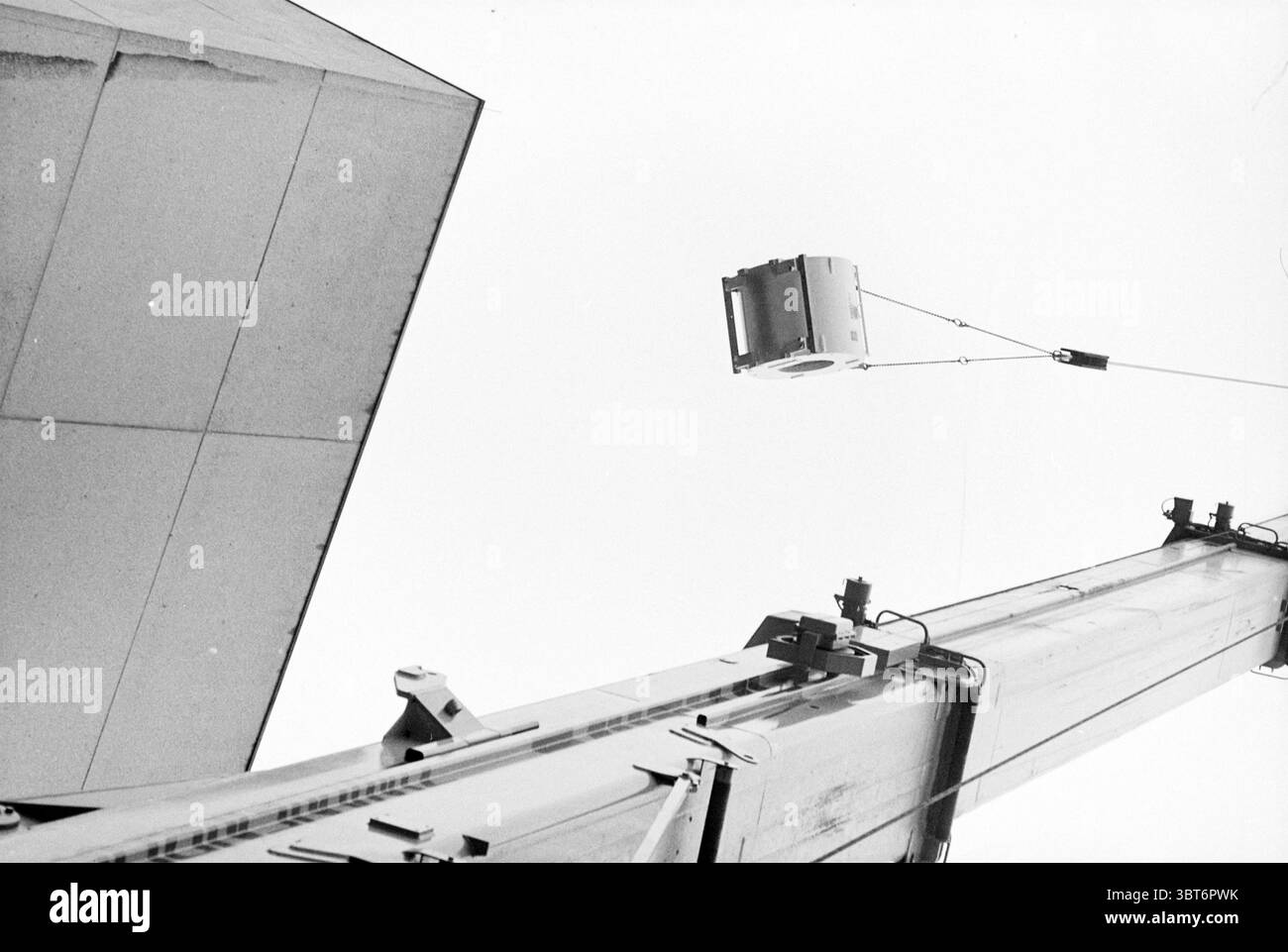 Lifting job at EG Haarlem [Elizabeth Gasthuis] Haarlem pays-Bas, Whizgle News, Dutch Desk, pays-Bas, 1950 - 2000 on 28-11-1994. Voici les rubriques de l'image. La scène capture une perspective montante saisissante, attirant l'attention du spectateur vers un objet suspendu contre un ciel pâle et expansif. L'objet, un grand conteneur rectangulaire, pend précairement à une grue robuste, qui domine la partie inférieure du cadre. La structure métallique de la grue est visible, présentant une série de boulons et de joints, suggérant résistance et fonctionnalité. En arrière-plan, un minimalis Banque D'Images