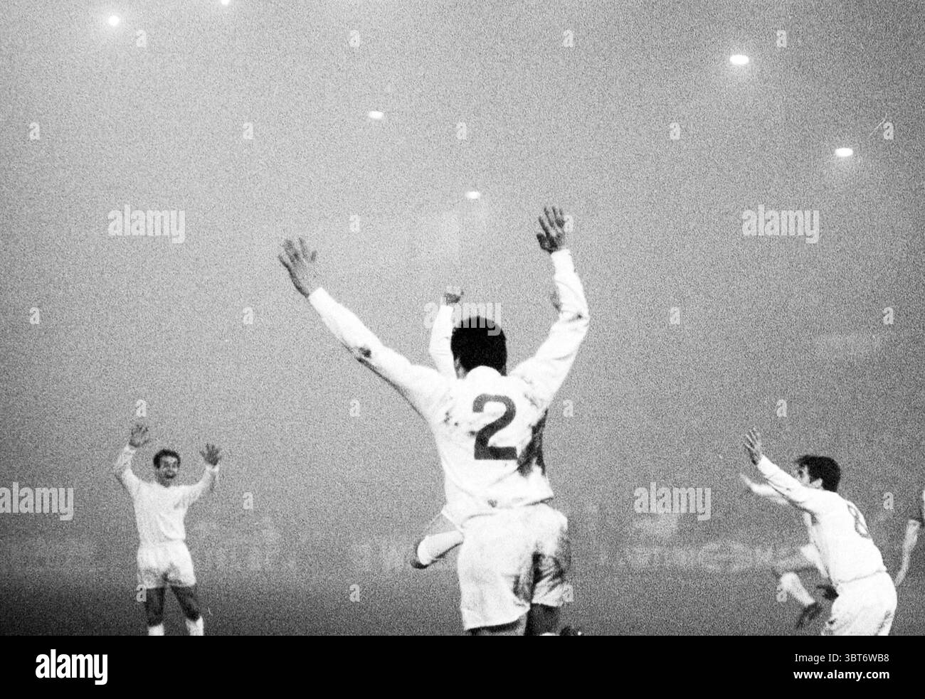 Match de football Ajax - Liverpool dans le brouillard Amsterdam pays-Bas, Whizgle News, Dutch Desk, pays-Bas, 1950 - 2000 le 07-12-1966. Ces rubriques apparaissent dans l'image. Dans une arène sportive brumeuse et atmosphérique, un groupe d'athlètes célèbre énergiquement. Le décor est obscurci par un épais brouillard, créant un sentiment de mystère et d'intensité. Les figurines sont revêtues d'uniformes blancs brillants, qui se démarquent sur la toile de fond terne, offrant un contraste saisissant. Un joueur, face à l'autre, a les bras levés haut en triomphe, révélant le chiffre '2' sur son dos. L'excitation de la victoire est Pal Banque D'Images