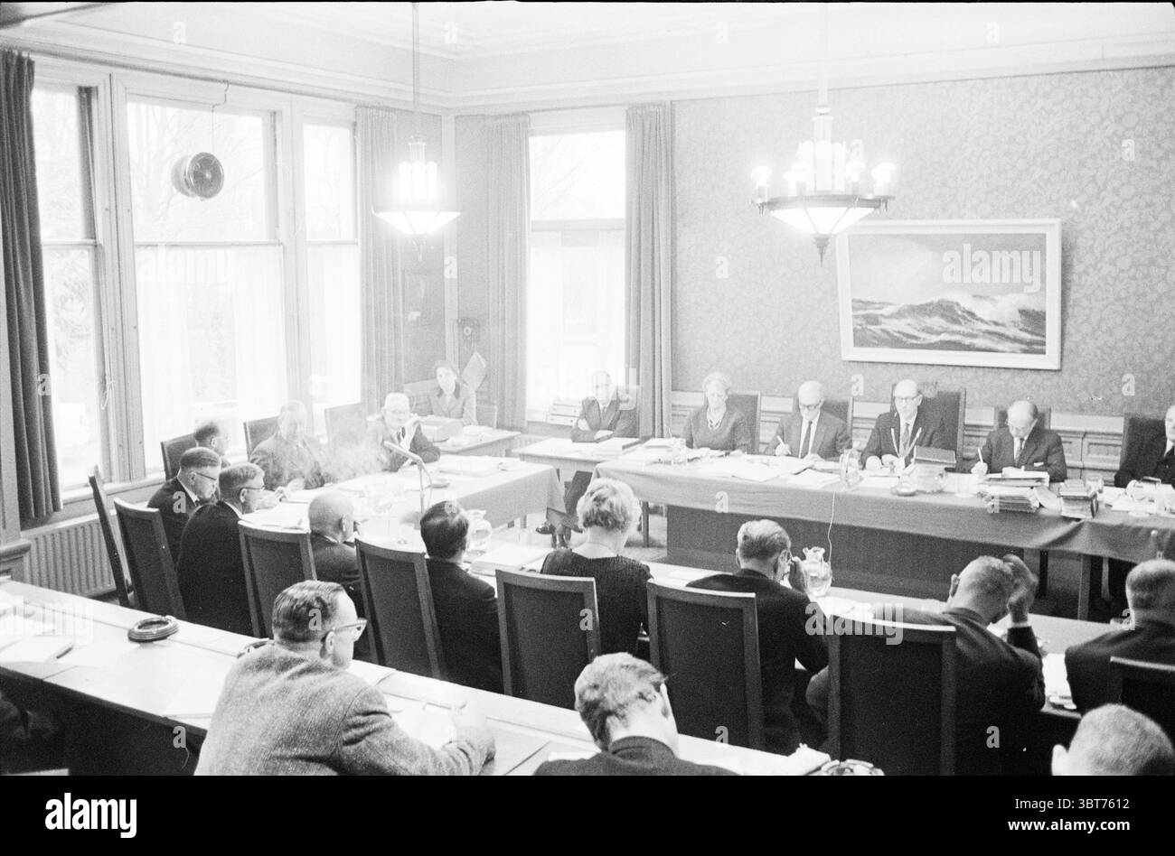 Budget débats Bloemendaal enfants enfants maisons d'enfants fête d'enfants enfants, Whizgle News, Dutch Desk, pays-Bas, 1950 - 2000 le 22-12-1961. Ces rubriques apparaissent dans l'image. La scène se déroule dans une salle de réunion formelle caractérisée par des couleurs discrètes et une atmosphère sombre. De longues tables, disposées de manière rectangulaire, dominent l'espace, entourées de chaises rembourrées, principalement dans des tons sombres. Le mobilier semble poli et digne, suggérant un environnement sérieux et professionnel. En tête de table, plusieurs individus sont positionnés, leurs expressions sérieuses Banque D'Images