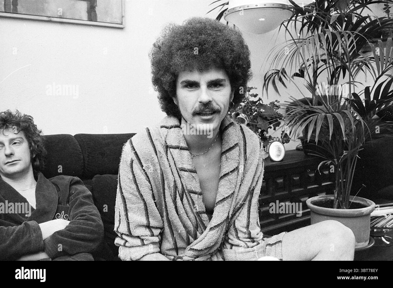 Répétition Robert long et N. Burg avec l'orchestre Robert long, Whizgle News, Dutch Desk, pays-Bas, 1950 - 2000 le 29-12-1975. Voici les rubriques de l'image. La scène met en scène deux individus assis dans un cadre intérieur confortable. Une personne, bien en vue au premier plan, a une coiffure afro arrondie distinctive et une moustache soigneusement soignée. Il porte une robe de couleur claire avec des rayures horizontales. Son expression semble détendue, et il établit un contact visuel avec le spectateur, suggérant la confiance. Le second individu est situé en arrière-plan, partiellement incliné et glissant Banque D'Images Répétition Robert long et N. Burg avec l'orchestre Robert long, Whizgle News, Dutch Desk, pays-Bas, 1950 - 2000 le 29-12-1975. Voici les rubriques de l'image. La scène met en scène deux individus assis dans un cadre intérieur confortable. Une personne, bien en vue au premier plan, a une coiffure afro arrondie distinctive et une moustache soigneusement soignée. Il porte une robe de couleur claire avec des rayures horizontales. Son expression semble détendue, et il établit un contact visuel avec le spectateur, suggérant la confiance. Le second individu est situé en arrière-plan, partiellement incliné et glissant Banque D'Images