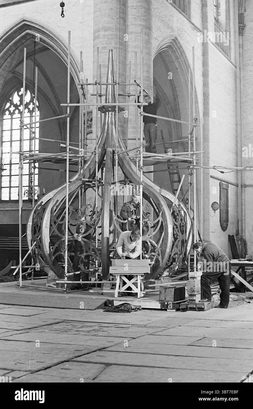 Travail sur l'oignon de la Grote ou Sint-Bavokerk tapant les spinnacles avec le plomb Grote Kerk Haarlem églises produit Bavokerk travail Haarlem Grote Markt pays-Bas, Whizgle News, Dutch Desk, pays-Bas, 1950 - 2000 on 02-02-1965. Voici les rubriques de l'image. La scène se déroule dans un intérieur spacieux, probablement une église ou une cathédrale, caractérisé par sa grande architecture. Les imposants murs en pierre s'élèvent haut, avec de grands vitraux qui infusent le cadre d'une lumière discrète, projetant des motifs doux et colorés sur le sol. Au premier plan, un grand lustre est sous constructi Banque D'Images