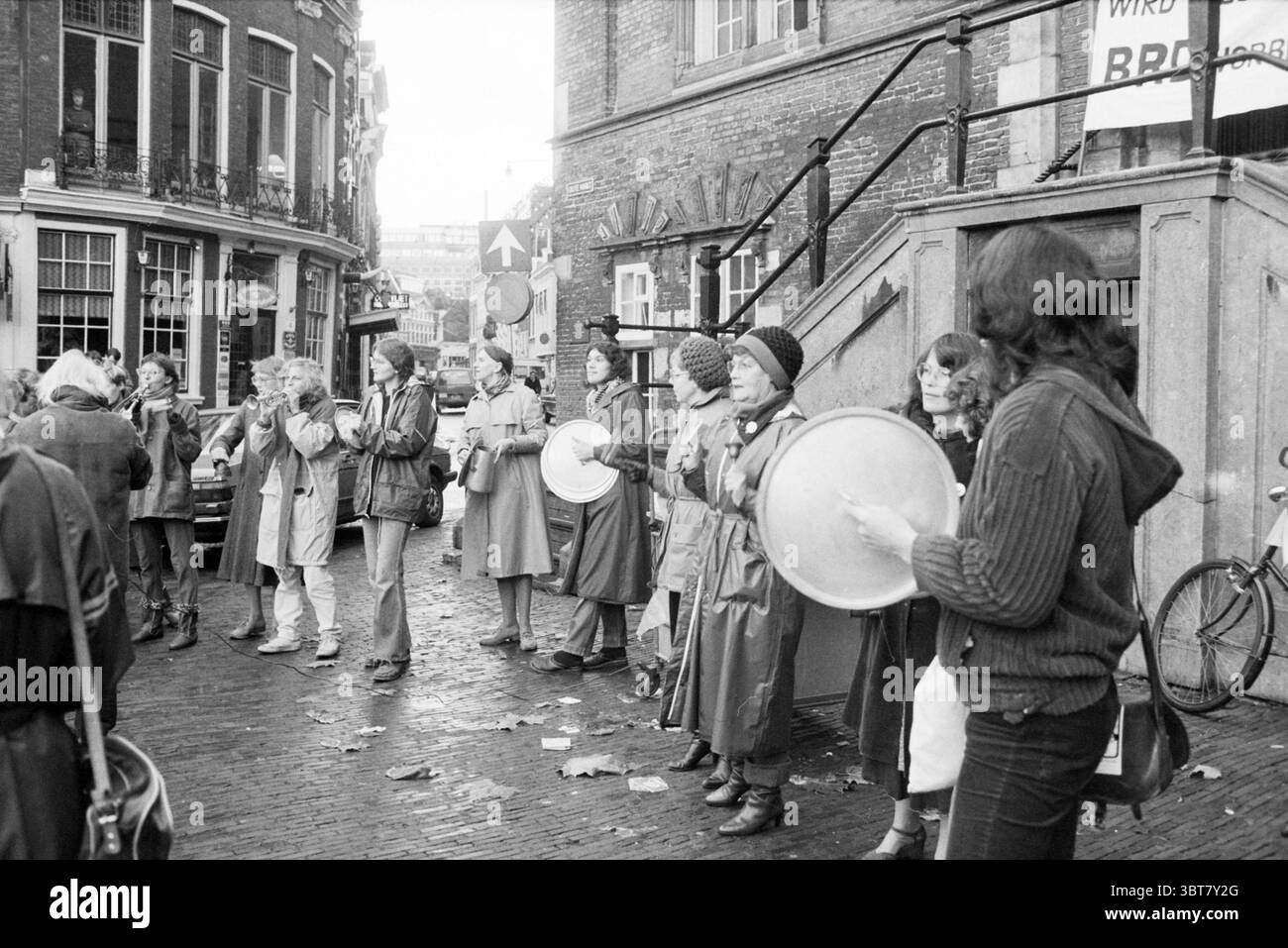 Bruit pour la paix Grote Markt Bonjour au revoir manifestations pour la paix Haarlem Grote Markt pays-Bas, Whizgle News, Dutch Desk, pays-Bas, 1950 - 2000 on 20-11-1983. L'image montre ces rubriques. La scène capture un rassemblement de rue animé, rempli d'enthousiasme et d'esprit communautaire. Au premier plan, un groupe diversifié de personnes se tient en demi-cercle, engagé et animé, suggérant une manifestation ou une célébration animée. Les individus portent un mélange de vêtements d'extérieur, y compris des manteaux longs et des chandails vibrants, mettant en valeur une palette de tons terreux discrets contrastant avec occasionnel Banque D'Images
