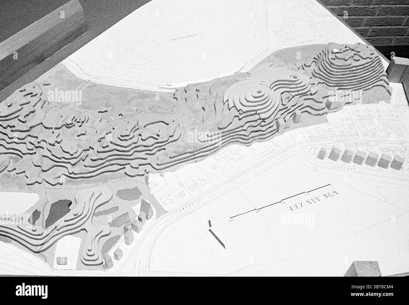 Planification : Model Dunes Wijk aan Zee Model, Whizgle News, Dutch Desk, The Netherlands, 1950 - 2000 sur 27-10-1975. L'image montre ces rubriques. La scène présente un modèle topographique détaillé d'un paysage. Le modèle est fabriqué à partir d'un matériau de couleur claire, probablement du plâtre ou une substance similaire, créant une représentation tridimensionnelle des collines et des vallées. Les contours sont minutieusement sculptés, illustrant les ondulations naturelles du terrain. Au premier plan, la surface du modèle présente une série de crêtes en couches, chacune variant en hauteur et en profondeur, suggérant une topographie accidentée. Th Banque D'Images