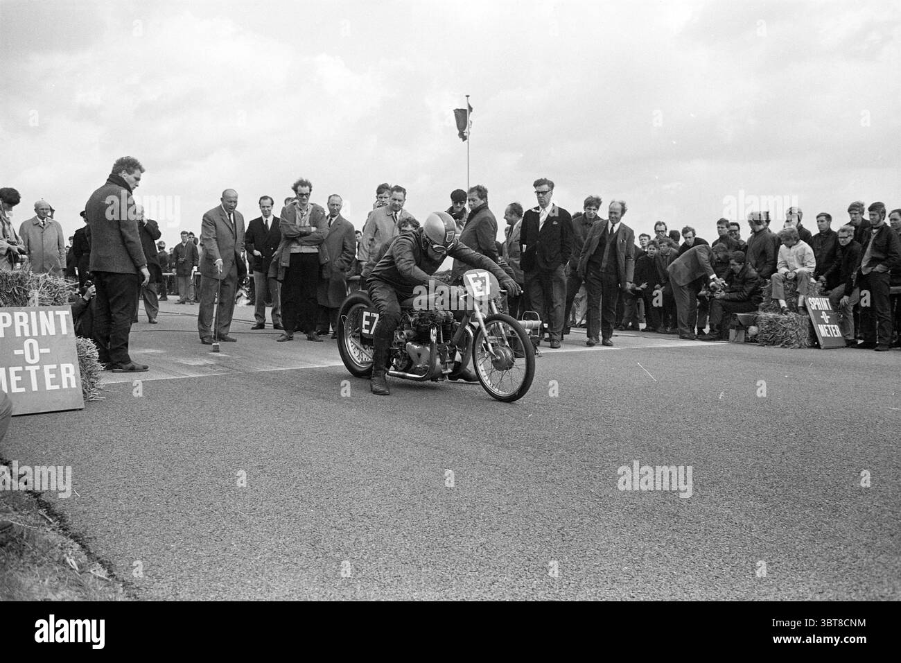 Motos sprint compétitions motos moto course, Whizgle News, Dutch Desk, pays-Bas, 1950 - 2000 le 21-09-1968. Ces rubriques apparaissent dans l'image. Dans la scène, un coureur de moto est positionné à l'avant-garde, accroupi bas sur la moto alors qu'il se prépare à accélérer. La moto a un design vintage, avec un cadre classique et des détails moteur proéminents qui transmettent une sensation de vitesse et de puissance. Autour du coureur, une foule diversifiée est réunie, allant des hommes vêtus de costumes et de chapeaux à d'autres dans une tenue plus décontractée, créant une riche tapisserie de styles de l'époque. De nombreuses sp Banque D'Images