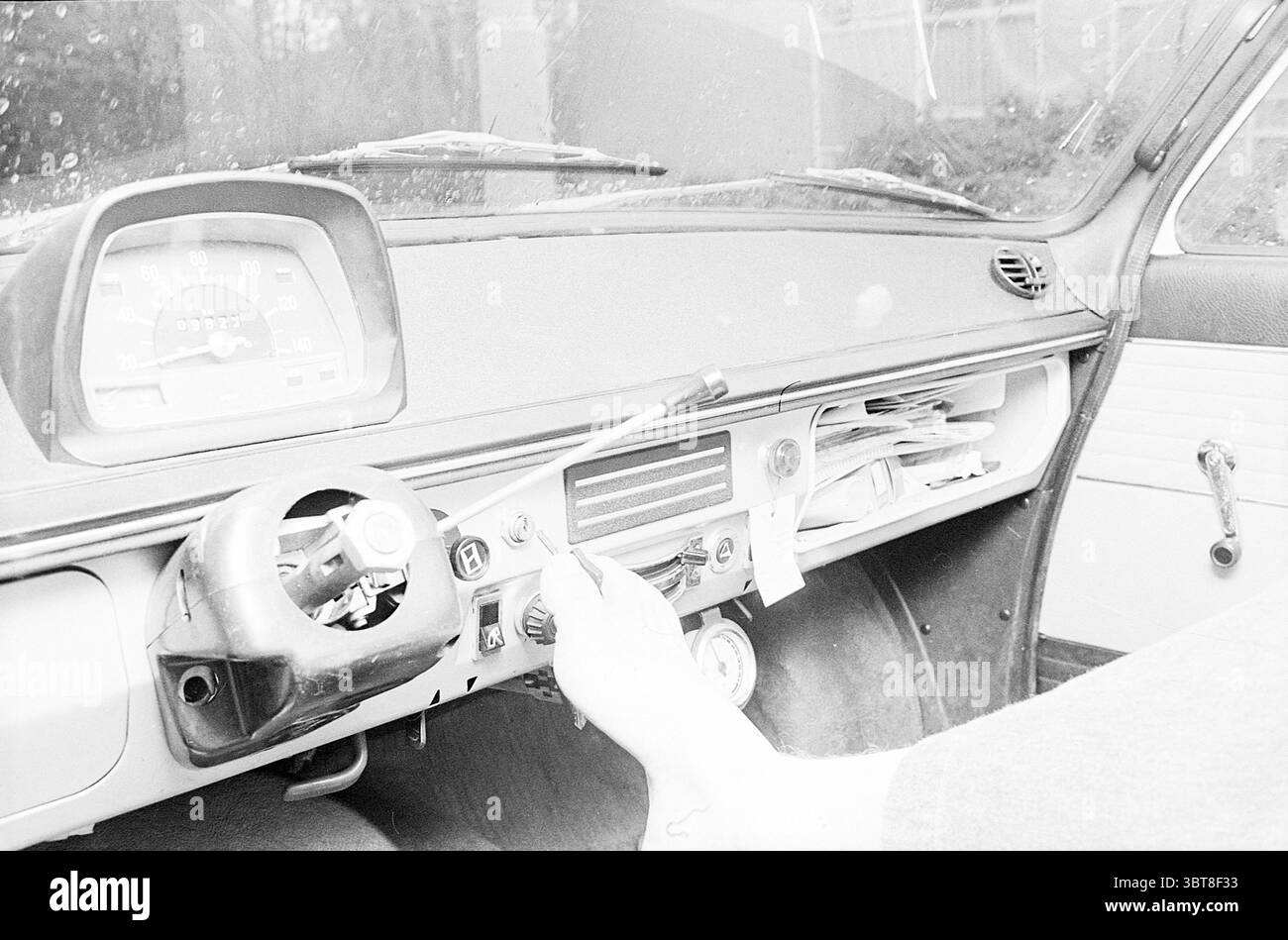 Voiture personnalisée pour Garçon sans mains C.B.R., Whizgle News, Dutch Desk, pays-Bas, 1950 - 2000 sur 09-05-1972. L'image inclut ces rubriques. La scène se concentre sur l'intérieur d'une voiture classique, mettant en valeur un mélange d'esthétique vintage et de design fonctionnel. Le tableau de bord dispose d'un compteur de vitesse proéminent et de divers cadrans, leurs visages avec un look légèrement usé suggérant l'âge et l'utilisation. La palette de couleurs se penche vers des tons discrets, principalement des gris et des blancs, avec des notes d'accents chromés qui captent la lumière. Il y a un éclat subtil sur certaines surfaces, probablement à partir des années d’usure, ce qui ajoute textu Banque D'Images