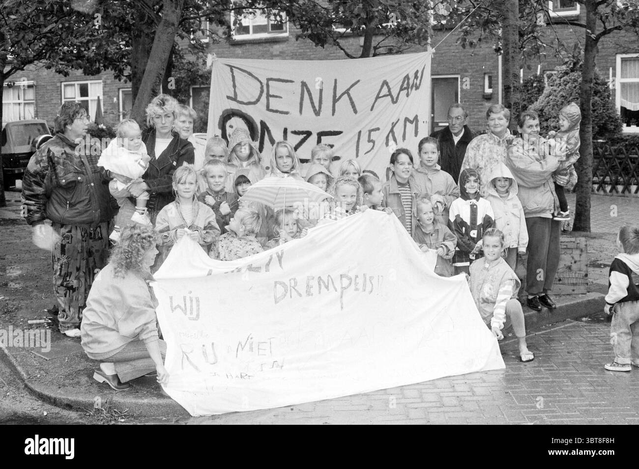 Groupe d'adultes et d'enfants avec la bannière 'pensez à nos enfants' Hillegom, Whizgle News, Dutch Desk, pays-Bas, 1950 - 2000 le 01-09-1992. L'image contient ces rubriques. La scène capture un grand groupe de personnes rassemblées à l'extérieur, exposées bien en vue dans une rue dans un quartier résidentiel. La majorité des individus, y compris de nombreux enfants et plusieurs adultes, sont orientés vers la caméra, leurs visages remplis d'une gamme d'expressions allant de la détermination à la joie. Les enfants, un mélange d'âges, sont habillés de vêtements décontractés, certains portant des vestes colorées et des imperméables, sugg Banque D'Images