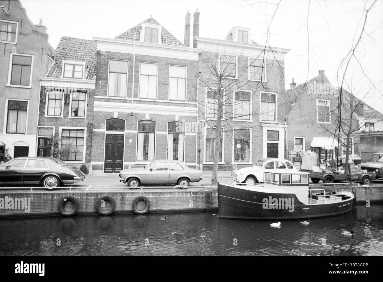 Bakenessergracht 33 Haarlem Bakenessergracht pays-Bas, Whizgle News, Dutch Desk, pays-Bas, 1950 - 2000 on 17-12-1990. Ces rubriques sont illustrées dans l'image. La scène présente un canal serein bordé de charmants bâtiments en briques. L'architecture présente un design néerlandais classique, caractérisé par de grandes fenêtres encadrées en blanc, avec une structure affichant une série de fenêtres hautes et étroites disposées symétriquement. Les toits présentent un mélange de profils à pignons et plats, certains ornés de cheminées. Au premier plan, un bateau épuré repose sur l'eau calme, sa coque sombre contrastée Banque D'Images