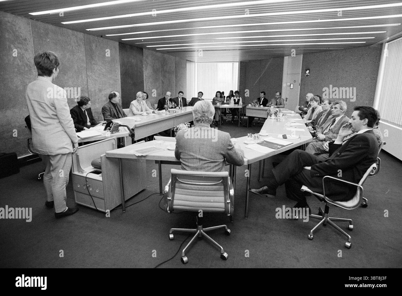 Réunion SFB Amsterdam Amsterdam pays-Bas, Whizgle News, Dutch Desk, pays-Bas, 1950 - 2000 le 17-03-1994. Ces rubriques apparaissent dans l'image. Une salle de conférence spacieuse et moderne est le cadre, caractérisé par un design minimaliste. Les murs sont composés d'un matériau gris foncé lisse qui contraste fortement avec le mobilier majoritairement clair. Une longue table rectangulaire domine le centre, disposée avec des surfaces polies et des papiers soigneusement alignés, suggérant une atmosphère de réunion formelle. Autour de la table, un groupe diversifié de personnes est assis. Ils présentent diverses expr Banque D'Images