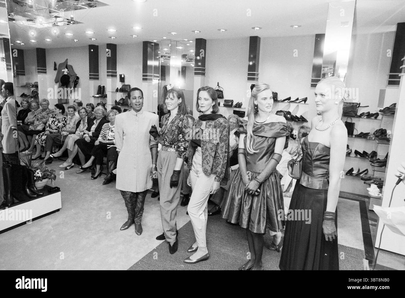 Défilé bon loeur Heemstede. Fashion Heemstede pays-Bas, Whizgle News, Dutch Desk, pays-Bas, 1950 - 2000 on 11-09-1989. L'image montre ces rubriques. Dans un cadre élégant, un groupe de cinq modèles se dresse sur une petite plate-forme, mettant en valeur les dernières tendances de la mode. Chaque modèle présente une tenue unique, contribuant à une tapisserie visuelle diversifiée. Le premier modèle porte une robe élégante et grise qui tombe juste au-dessus des genoux, complétée par des bas sombres à hauteur des genoux. Le second modèle présente un look plus flamboyant avec une blouse volumineuse jumelée à une jupe ajustée, ornée Banque D'Images