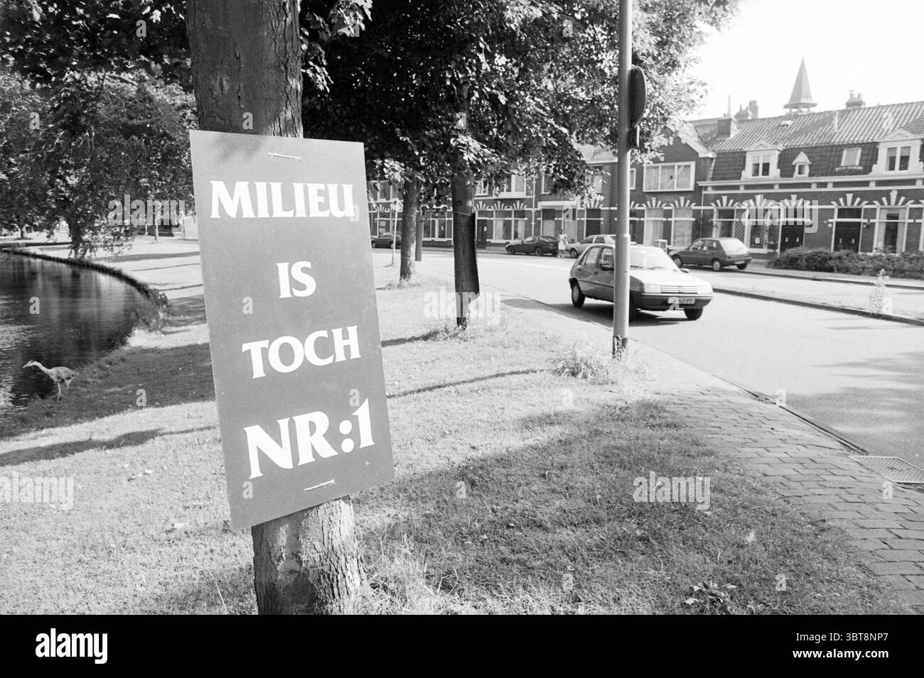 Signe de protestation Kinderhuissingel Haarlem Kinderhuissingel pays-Bas, Whizgle News, Dutch Desk, pays-Bas, 1950 - 2000 le 16-06-1993. L'image montre ces rubriques. Dans la scène, un cadre de rue dynamique est capturé avec un sens de la vie urbaine. À gauche, un signe proéminent est apposé sur un arbre, affiché audacieusement en noir et blanc, sa grande police attirant l'attention du spectateur. Cela contraste avec les feuilles vertes luxuriantes et le tronc de l'arbre, évoquant un sentiment de nature se mêlant à l'environnement bâti. À droite, une chaussée bien entretenue s'étend dans la scène Banque D'Images