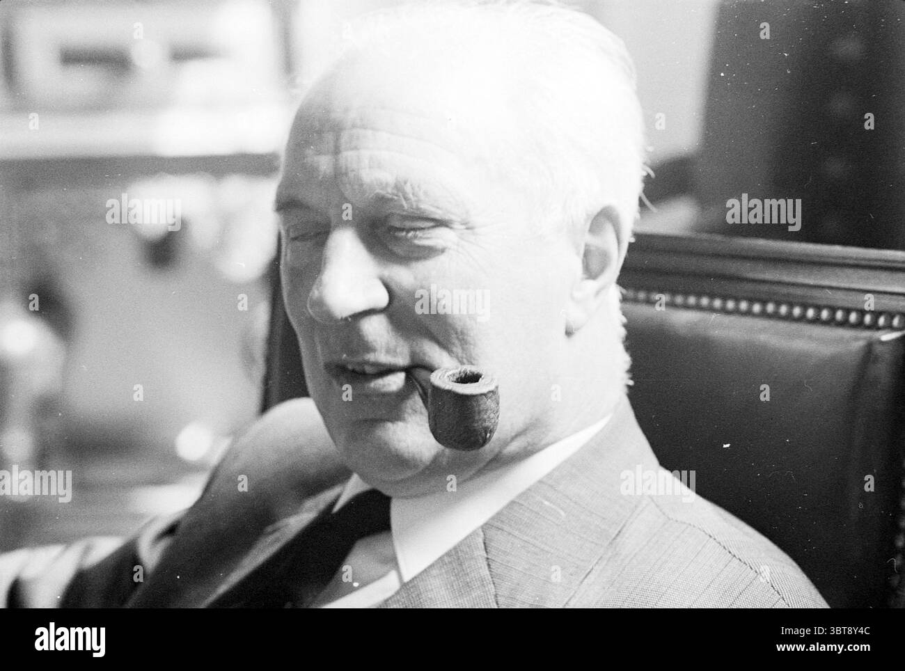 Portrait de Mayor Cremers Mayors, Whizgle News, Dutch Desk, pays-Bas, 1950 - 2000 on 07-05-1969. Ces rubriques sont illustrées dans l'image. Un individu bien habillé est confortablement assis dans une chaise richement rembourrée, la texture du tissu paraissant douce et accueillante. Ses cheveux de couleur claire, soignés, contrastent avec le costume plus sombre qu'il porte, qui est taillé sur mesure et pointu. Une pipe repose légèrement entre ses lèvres, faisant allusion à un moment de détente ou de contemplation. L'arrière-plan présente des couleurs tamisées, éventuellement avec des boiseries ou des meubles élégants qui suggèrent une atmosphère de sophi Banque D'Images