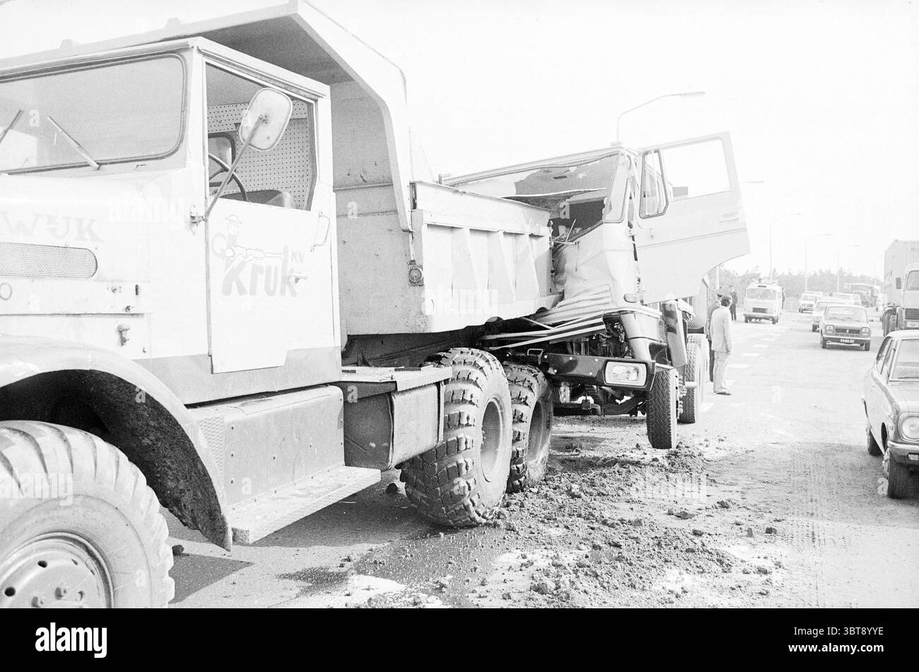 2 camions sur Rijksweg 9 à Beverwijk accidents collisions accidents, Whizgle News, Dutch Desk, pays-Bas, 1950 - 2000 on 25-06-1974. Ces rubriques apparaissent dans l'image. La scène représente un accident de la circulation sur une chaussée très fréquentée, dominée par deux gros camions. Le premier camion, un camion à benne basculante, est partiellement chargé de terre ou de débris, son lit incliné vers le haut, montrant la cargaison se déversant sur le bord. Le camion est peint dans une couleur décolorée, peut-être bleue ou grise, avec des restes d'un vieux logo qui font allusion à une marque autrefois dynamique. Le deuxième camion, positionné à un angle, semble avoir un signe soutenu Banque D'Images