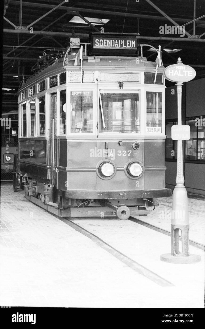 Musée du tramway NZH Noord Zuid Hollandse Vervoersmaatschappij N.V. NZ Tram, Whizgle News, Dutch Desk, pays-Bas, 1950 - 2000 on 05-11-1986. L'image contient ces rubriques. La scène présente un tramway vintage positionné sur ses rails, suggérant une ambiance historique ou nostalgique. Le tramway a une couleur profonde et riche, probablement un mélange de verts foncés et de bruns, soulignant son design classique. Sa face avant affiche de grandes fenêtres à plusieurs volets qui reflètent l'environnement, créant un sentiment de connectivité avec l'environnement. L'arrière du tramway est orné d'un petit panneau indiquant sa destination, contras Banque D'Images