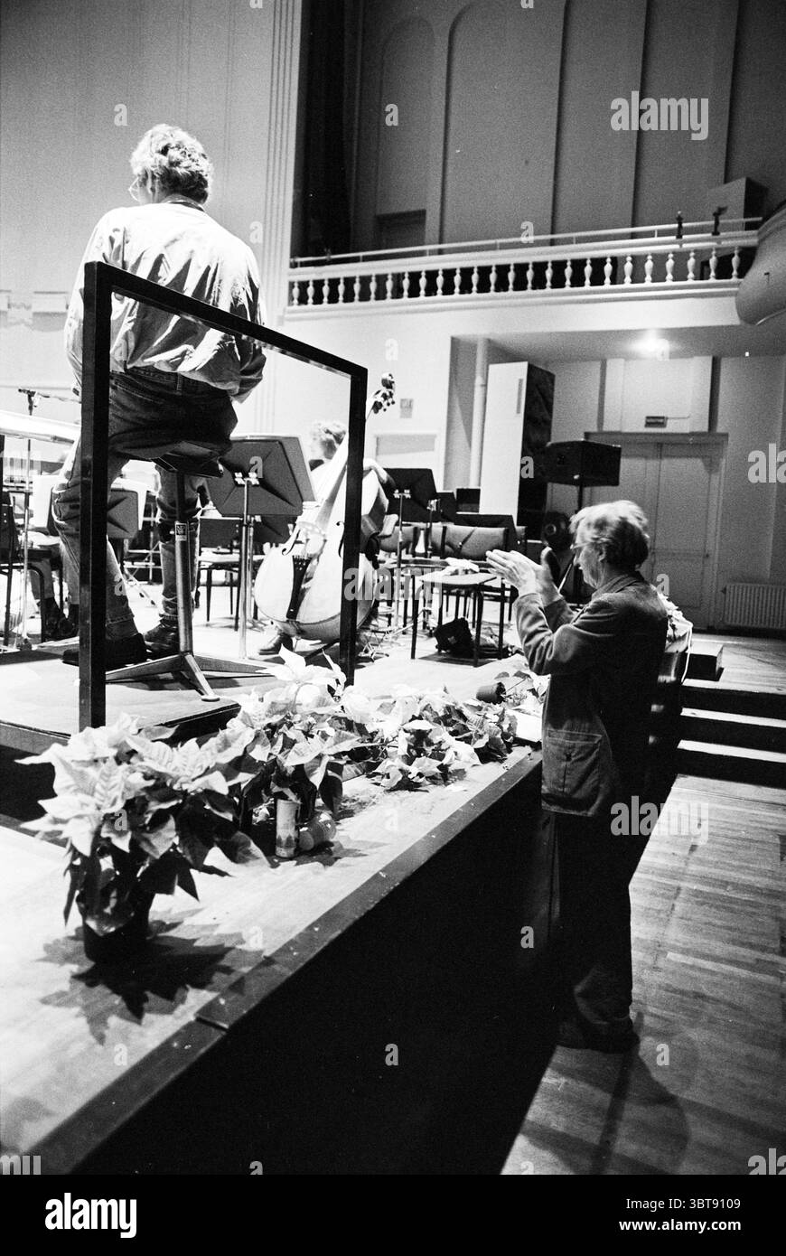 Rep. NPhO ton de Leeuw, Whizgle News, Dutch Desk, pays-Bas, 1950 - 2000 on 20-12-1994. L'image montre ces rubriques. La scène capture un moment dynamique dans un espace de performance, où l'accent est mis sur un musicien assis positionné à un perchoir surélevé. Le musicien, aux cheveux dégoûtés, est habillé de façon décontractée, partiellement obscurci par un simple cadre noir qui sert de toile de fond. Ci-dessous, sur le sol, un petit spectateur, un gentleman plus âgé en costume sombre, applaudit avec enthousiasme, incarnant la joie et l'appréciation. Son expression est une expression d'admiration, mettant en évidence un lien avec la musique étant pe Banque D'Images