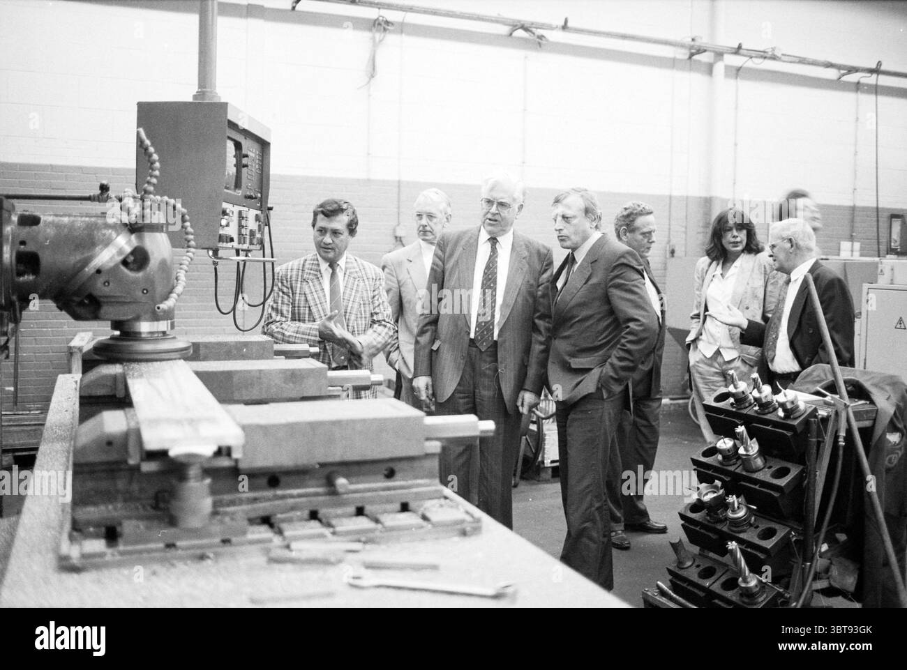 Visitez Van Gelder à Dietvoorst IJmuiden IJmuiden Nederland, Whizgle News, Dutch Desk, pays-Bas, 1950 - 2000 le 22-09-1991. L'image inclut ces rubriques. Dans un cadre industriel spacieux, un groupe d'individus est rassemblé autour d'une grande machine métallique, qui domine le premier plan. La machine, potentiellement un outil de fraisage ou d'usinage, comporte divers leviers et cadrans, dont l'un est engagé en évidence, indiquant une utilisation active. Les individus, un mélange d'hommes et de femmes, varient dans la tenue de formel à semi-formel. Certains portent des costumes dans des tons discrets comme le gris et la marine, tandis que d'autres portent du pla Banque D'Images