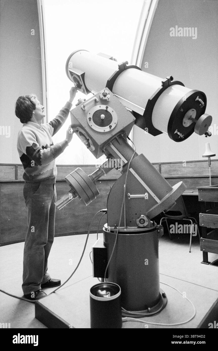 Observatoire public Copernicus Vergierdeweg Observatoire Haarlem Vergierdeweg pays-Bas, Whizgle News, Dutch Desk, pays-Bas, 1950 - 2000 on 04-12-1985. L'image inclut ces rubriques. La scène capture l'intérieur d'un observatoire, caractérisé par son plafond en forme de dôme qui permet une observation céleste. Au centre de la composition se trouve un grand télescope sophistiqué, élégamment conçu avec une base métallique robuste et un corps cylindrique blanc immaculé. Ce télescope est incliné vers le haut, suggérant une disponibilité pour l'observation céleste. Une personne se tient à côté de l'appareil, interagissant wi Banque D'Images