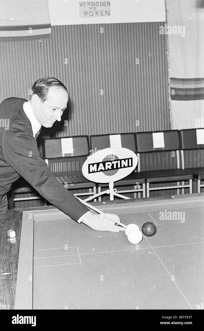 Joueur de billard, Whizgle News, Dutch Desk, pays-Bas, 1950 - 2000 sur 01-1966. L'image contient ces rubriques. Dans la scène, un homme est prêt au-dessus d'une table de billard, se préparant intentionnellement à faire un tir. Il porte un costume pointu et sombre qui contraste avec les tons clairs de la surface de la table de billard. Son expression reflète la concentration, avec des sourcils légèrement sillonnés et des lèvres pressées l'une contre l'autre. La table est équipée de boules de billard distinctives, une blanche et une sombre, positionnées étroitement ensemble. La boule blanche est près du bord de la table, tandis que la boule sombre est à une courte distance, Banque D'Images