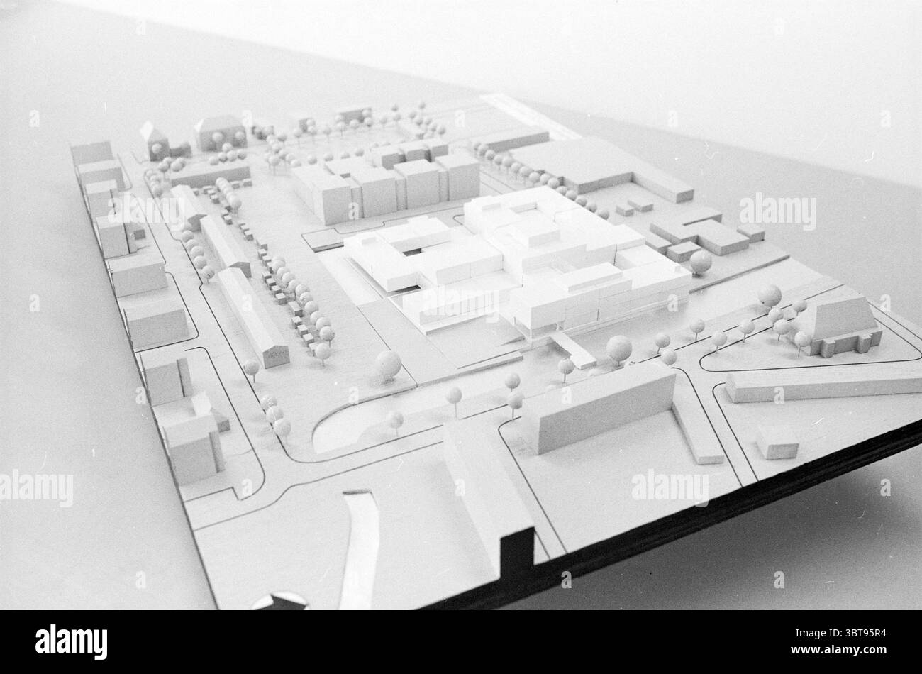 Plan de construction modèle Haarlem Agence des bâtiments gouvernementaux modèle Haarlem pays-Bas, Whizgle News, Dutch Desk, pays-Bas, 1950 - 2000 le 08-03-1988. Ce sont les éléments de l'image. La scène présente un modèle architectural méticuleusement conçu sur un fond minimaliste. Le modèle présente une vue plongeante d'une zone urbaine planifiée, avec une variété de structures et d'espaces disposés dans un arrangement réfléchi. Un groupe de bâtiments occupe la zone centrale, principalement représentée en blanc, ce qui lui confère une esthétique propre et moderne. La conception met l'accent sur la forme géométrique Banque D'Images