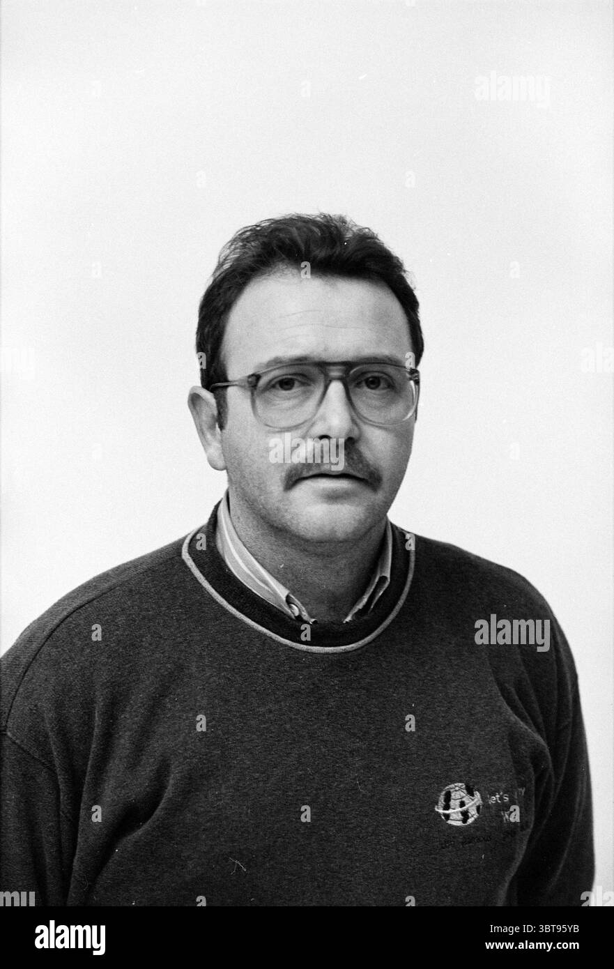 Photo de passeport Karel Jansen, Whizgle News, Dutch Desk, pays-Bas, 1950 - 2000 le 22-12-1992. Ce sont les éléments de l'image. Dans la scène, un homme est positionné au centre, donnant à la composition une mise au point solide. Il a les cheveux foncés et bien peignés, et une moustache subtile qui accentue ses traits du visage. Son expression est sérieuse mais calme, suggérant un sens de contemplation. Il porte un pull sombre superposé sur une chemise à col clair, la juxtaposition des couleurs apportant un contraste qui attire l'attention sur lui. L'arrière-plan est un ton clair et lisse qui met en valeur le sujet Banque D'Images