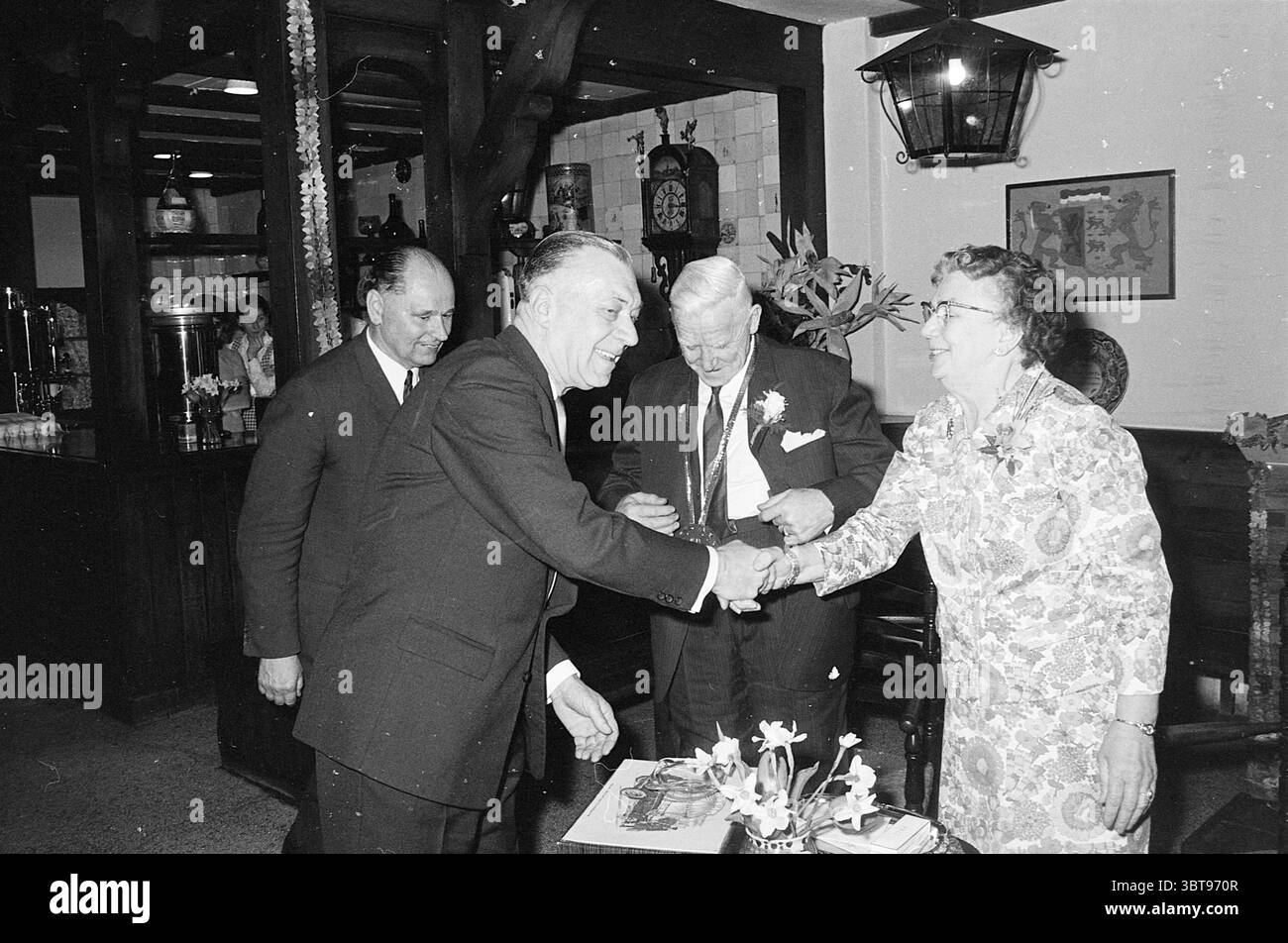 Mr. van Dijck 50 ans à Union Chocolate Jubilee anniversaires Union Chocolate Factory Haarlem Paul Krugerkade pays-Bas, Whizgle News, Dutch Desk, pays-Bas, 1950 - 2000 on 14-05-1969. L'image inclut ces rubriques. Dans un intérieur chaleureusement éclairé, la scène capture un moment de célébration et d'interaction entre un groupe de quatre personnes. Le cadre dégage une atmosphère classique et accueillante, caractérisée par des poutres en bois sombre et un décor traditionnel, suggérant un espace qui peut être un restaurant ou une salle de réunion. Deux hommes, habillés en tenue formelle - un costume sombre pour un et un de couleur claire Banque D'Images