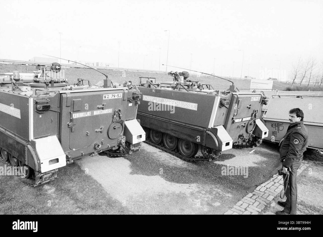 Voitures blindées sur les routes d'accès de Schiphol Schiphol Schiphol, Whizgle News, Dutch Desk, pays-Bas, 1950 - 2000 le 08-03-1990. L'image contient ces rubriques. La scène montre un groupe de véhicules militaires stationnés sur un terrain accidenté, caractérisé par du gravier et des taches d'herbe. Trois véhicules blindés de transport de troupes sont disposés étroitement ensemble, leurs surfaces métalliques présentant un fini mat avec des tons doux de gris et vert olive. Ces véhicules sont équipés de structures en forme de tourelle sur le dessus, suggérant une disponibilité pour l'action, tandis que les pistes indiquent leur capacité à naviguer dans le grou rugueux Banque D'Images