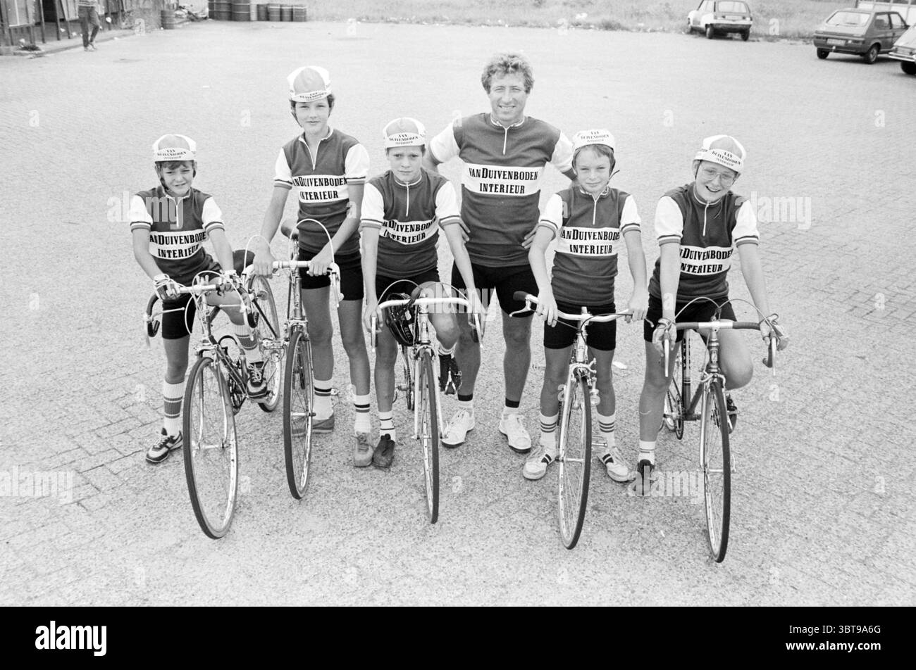 Équipes Mosquito Round Mosquito Round, Whizgle News, Dutch Desk, pays-Bas, 1950 - 2000 sur 31-07-1983. Ces rubriques sont illustrées dans l'image. La scène montre un groupe de cinq jeunes cyclistes posés avec confiance sur leurs vélos, avec un homme d'âge moyen debout à leurs côtés. Les six individus sont habillés de maillots de cyclisme assortis, qui sont principalement sombres avec des couleurs audacieuses et contrastées qui suggèrent une affiliation à une équipe. Les maillots présentent un design distinct, indiquant peut-être un club cycliste local ou un sponsor. Les cyclistes affichent un mélange d'expressions, allant de sourires joyeux à focu Banque D'Images