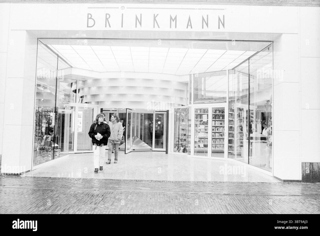 Entrée Brinkmann passage Brinkmann passage Haarlem pays-Bas, Whizgle News, Dutch Desk, pays-Bas, 1950 - 2000 le 03-03-1988. Ces rubriques sont illustrées dans l'image. La scène capture une entrée de commerce moderne avec de vastes portes vitrées partiellement ouvertes, révélant de manière tonitruante l'intérieur. La devanture est encadrée en blanc élégant, donnant un look épuré et contemporain. À travers le verre, un affichage bien organisé de divers articles est visible à l'intérieur, disposés soigneusement le long des murs. À l'extérieur de l'entrée, quelques individus se tiennent bien en vue. Une personne, avec un distinctif Banque D'Images