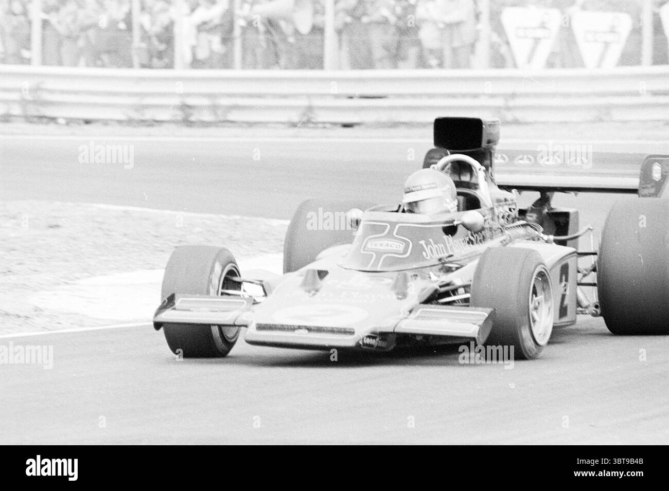 Autorace circuit Zandvoort Zandvoort., Whizgle News, Dutch Desk, pays-Bas, 1950 - 2000. L'image contient ces rubriques. La scène capture un moment dynamique dans un événement de sport automobile, mettant en vedette une voiture de course élégante en mouvement, positionnée excentrée lorsqu'elle suit une courbe sur la piste. La voiture bénéficie d'une combinaison éclatante de rouge profond et de noir, avec des logos de sponsor bien en vue sur sa carrosserie. La conception aérodynamique du véhicule met l'accent sur la vitesse, avec un nez allongé et des pneus larges qui adhèrent à l'asphalte. Autour de la voiture, une toile de fond floue révèle l'excitation de la Banque D'Images