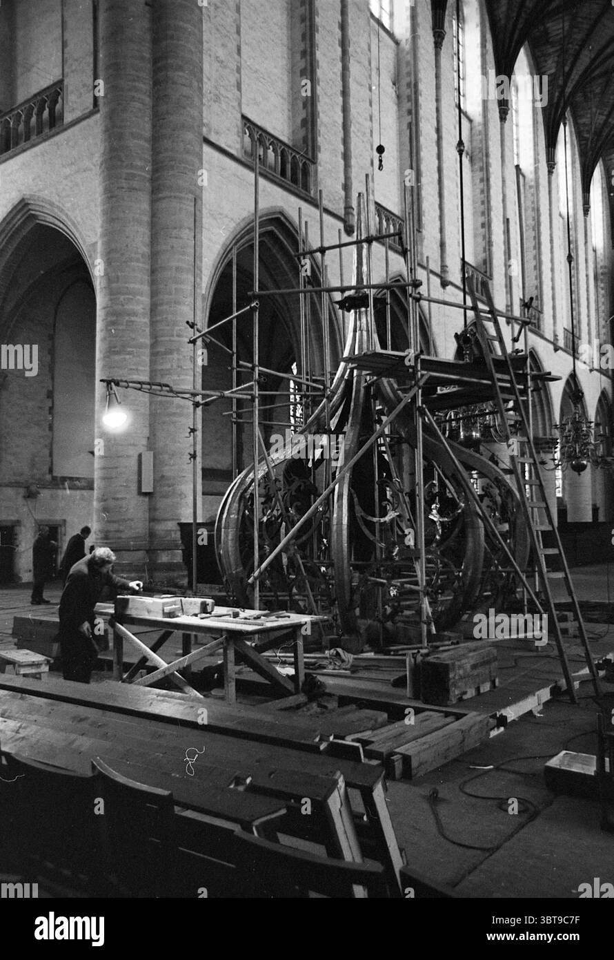 Travail sur l'oignon de la Grote ou Sint-Bavokerk tapant les spinnacles avec le plomb Grote Kerk Haarlem églises produit Bavokerk travail Haarlem Grote Markt pays-Bas, Whizgle News, Dutch Desk, pays-Bas, 1950 - 2000 on 02-02-1965. L'image montre ces rubriques. La scène capture l'intérieur d'un vaste espace ressemblant à une cathédrale caractérisé par de hautes arches en pierre et de grandes fenêtres éclairées qui laissent passer la lumière douce et diffuse. L'architecture transmet un sentiment de grandeur, avec les hauts plafonds accentuant la hauteur et l'espace de l'environnement. Au premier plan, une méta Banque D'Images