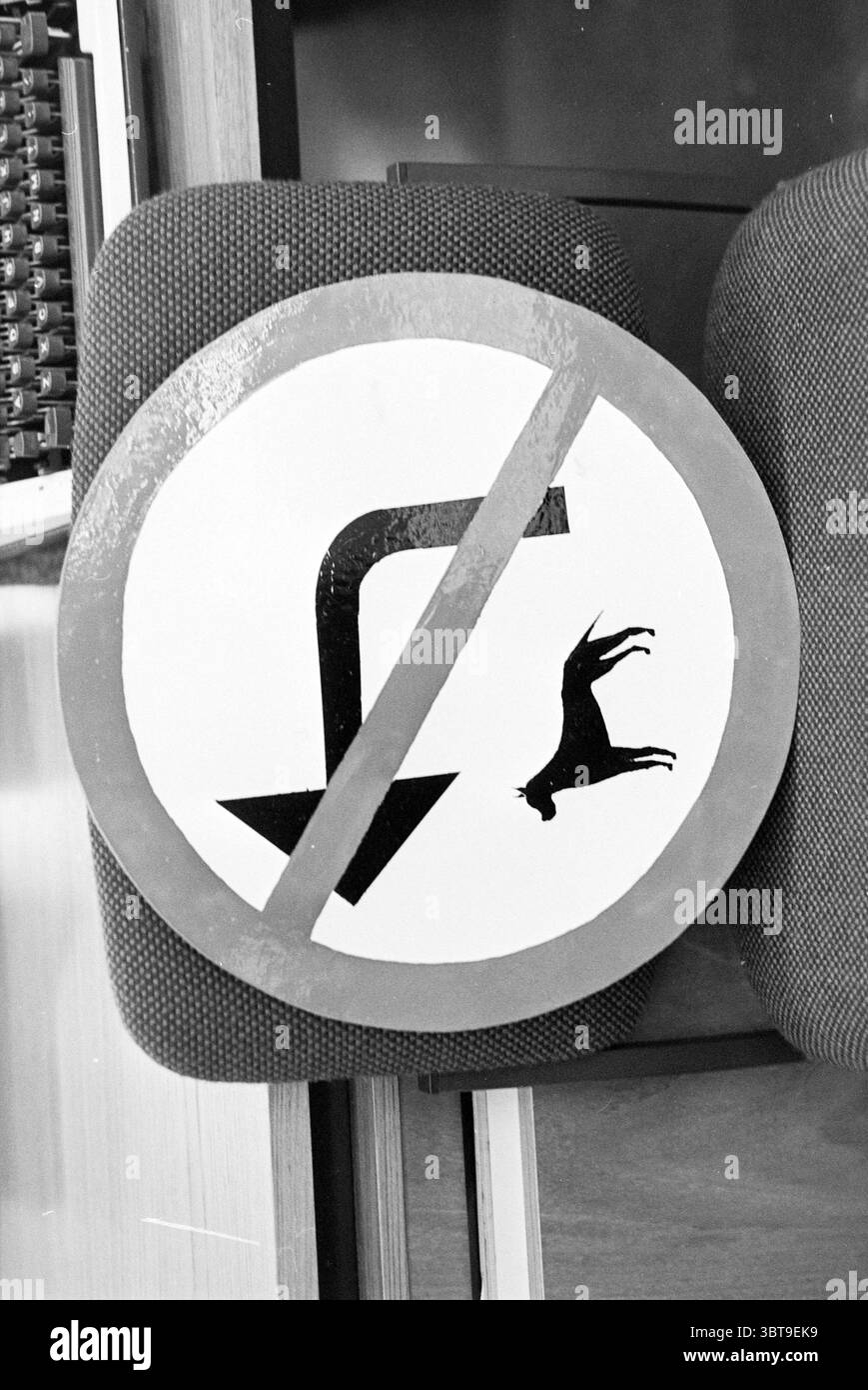 Signe d'interdiction de chien IJm. Signes chiens IJmuiden pays-Bas, Whizgle News, Dutch Desk, pays-Bas, 1950 - 2000 sur 28-11-1979. Ces rubriques sont illustrées dans l'image. La scène présente un panneau circulaire bien en vue sur une toile de fond qui suggère un environnement structuré, peut-être un espace intérieur. Le signe est défini par une bordure rouge audacieuse entourant l'imagerie centrale, ce qui traduit une interdiction claire. À l’intérieur du cercle, une flèche vers le bas indique la direction, tandis qu’une icône représentant un chien à la mi-automne est représentée, suggérant une interprétation humoristique ou fantaisiste d’une directive « non », lik Banque D'Images