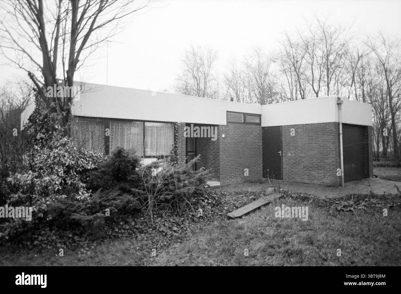 Extérieur résidence officielle Heimanshof Hoofddorp maisons extérieures et construction de maisons Hoofddorp Wieger Bruinlaan pays-Bas, Whizgle News, Dutch Desk, pays-Bas, 1950 - 2000 on 10-01-1990. Ces rubriques sont illustrées dans l'image. La scène représente une maison moderne et minimaliste caractérisée par un toit plat et des lignes épurées. La structure est construite à partir d'une combinaison de briques et de panneaux blancs lisses, créant un contraste frappant entre les deux matériaux. D'un côté, de grandes fenêtres permettent d'apercevoir l'intérieur, où les rideaux transparents diffusent la lumière, laissant entendre une atmosphère chaleureuse insi Banque D'Images