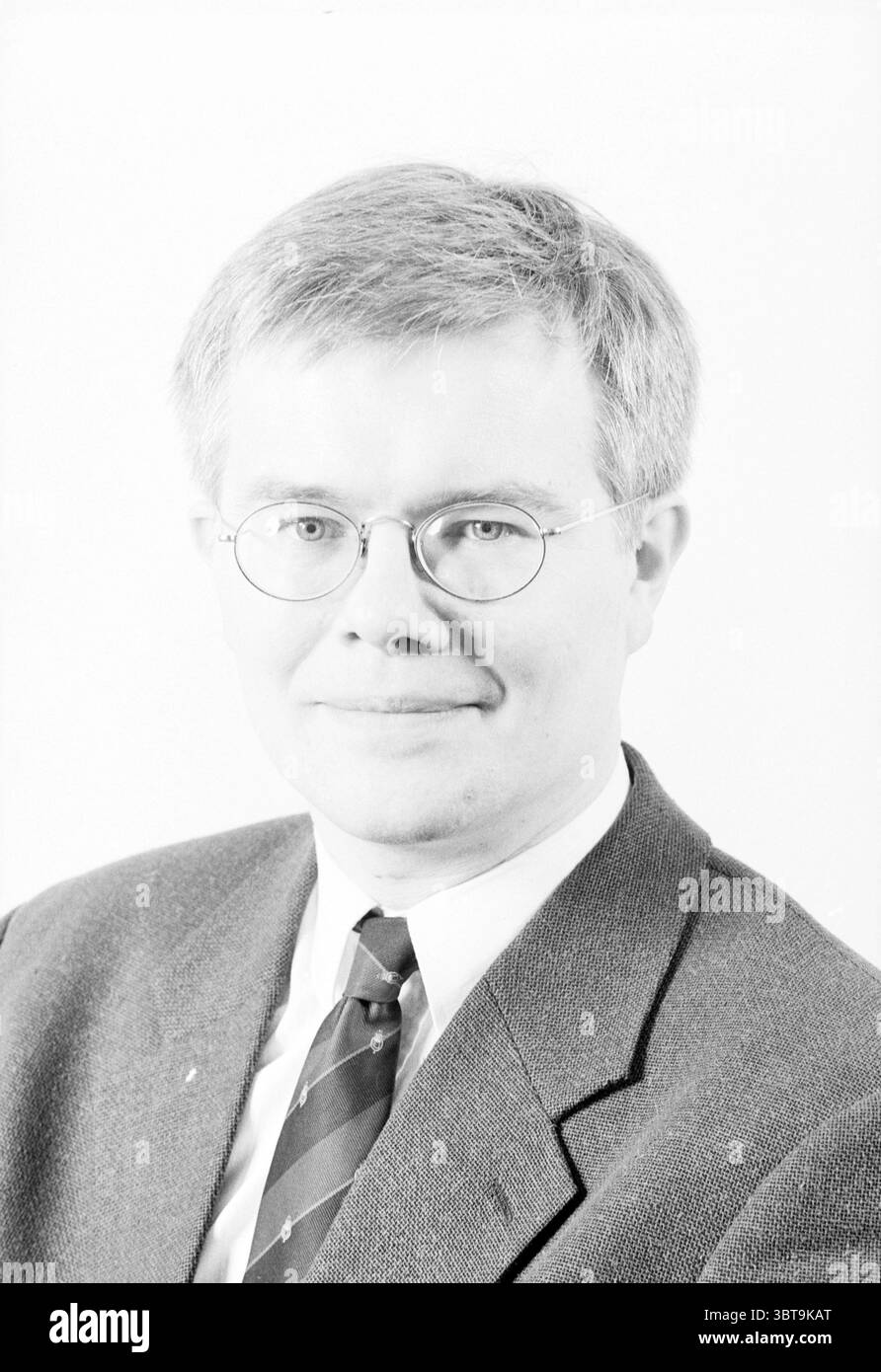 Portraits Chambre de commerce à Haarlem Haarlem pays-Bas, Whizgle News, Dutch Desk, pays-Bas, 1950 - 2000 sur 21-01-1996. Voici les rubriques de l'image. La scène met en scène un homme aux cheveux courts et clairs, habillé dans une tenue professionnelle qui comprend un blazer foncé et une chemise blanche. Il porte des lunettes rondes qui ajoutent à son apparence savante. Sa cravate présente un motif subtil qui contraste avec les couleurs Unies de ses vêtements. L'arrière-plan est une nuance douce et neutre qui met en valeur le sujet. L'éclairage est lumineux et uniforme, éclairant son visage et le point culminant Banque D'Images