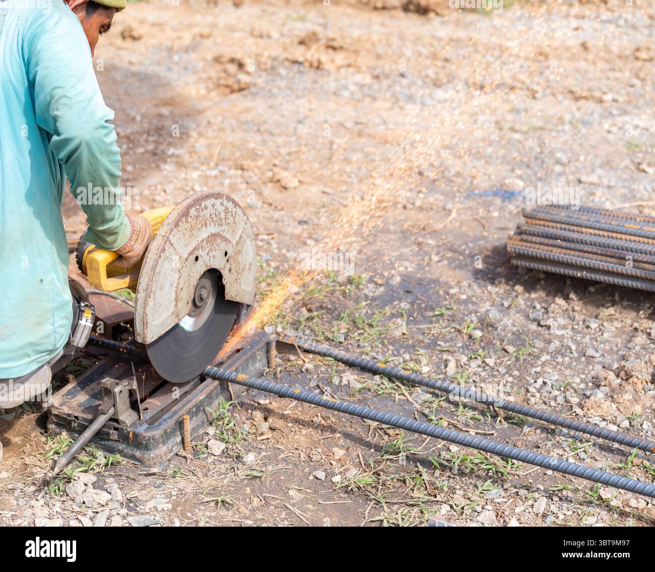 L'ouvrier coupant des barres d'armature avec une machine de coupe de fibre dans le chantier de construction. Banque D'Images
