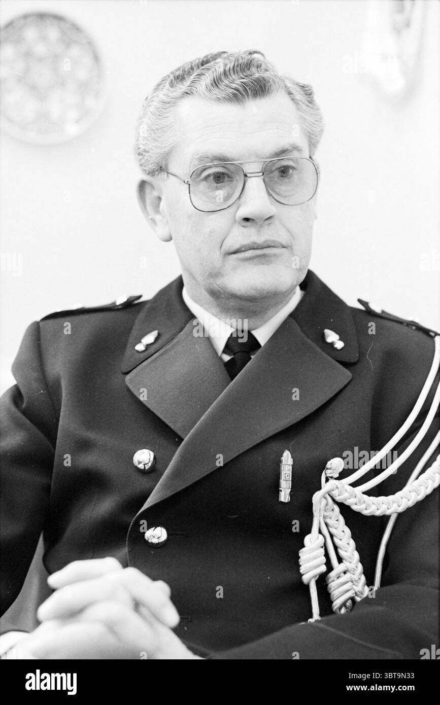 Pompiers éteints. Borst chef de la prévention des incendies Haarlem pompiers Haarlem pays-Bas, Whizgle News, Dutch Desk, pays-Bas, 1950 - 2000 on 15-02-1985. L'image inclut ces rubriques. La scène capture une personne assise, dégageant un sens de l'autorité et du professionnalisme. Il est habillé d'un uniforme sombre formel, qui comporte des insignes distincts qui signifient le rang ou le rôle, ajoutant une couche de gravitas à son apparence. L'uniforme est soigneusement adapté, mettant l'accent sur un sens de l'ordre et de la discipline. Ses lunettes, avec une légère teinte, encadrent son visage, indiquant la profondeur intellectuelle. Banque D'Images