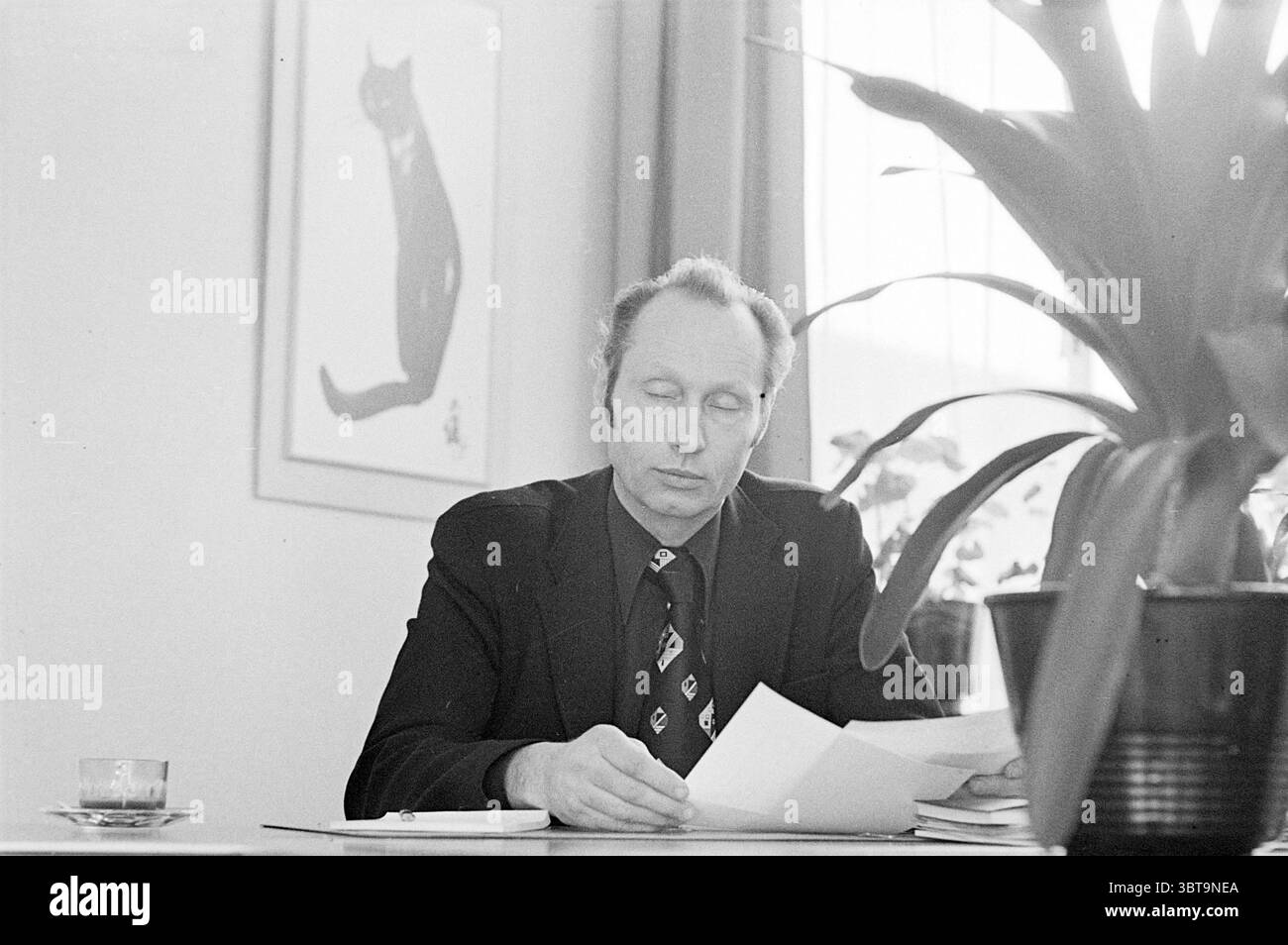 H.I.P. Hock moral police Amsterdam + voiture de contrôle radar sur le Glipperdreef police Heemstede Glipper Dreef pays-Bas, Whizgle News, Dutch Desk, pays-Bas, 1950 - 2000 on 10-02-1975. L'image montre ces rubriques. Dans une pièce ensoleillée, un homme est assis à une table en bois, profondément engagé dans l'examen de documents. Il porte un costume sombre, complété par une cravate à motifs qui ajoute une touche de personnalité à sa tenue. Ses cheveux sont soigneusement coiffés, et il a l'air pensif, avec ses yeux concentrés sur les papiers devant lui. Derrière lui, une grande fenêtre permet à la lumière douce et diffuse de couler dans l'espace, casti Banque D'Images H.I.P. Hock moral police Amsterdam + voiture de contrôle radar sur le Glipperdreef police Heemstede Glipper Dreef pays-Bas, Whizgle News, Dutch Desk, pays-Bas, 1950 - 2000 on 10-02-1975. L'image montre ces rubriques. Dans une pièce ensoleillée, un homme est assis à une table en bois, profondément engagé dans l'examen de documents. Il porte un costume sombre, complété par une cravate à motifs qui ajoute une touche de personnalité à sa tenue. Ses cheveux sont soigneusement coiffés, et il a l'air pensif, avec ses yeux concentrés sur les papiers devant lui. Derrière lui, une grande fenêtre permet à la lumière douce et diffuse de couler dans l'espace, casti Banque D'Images