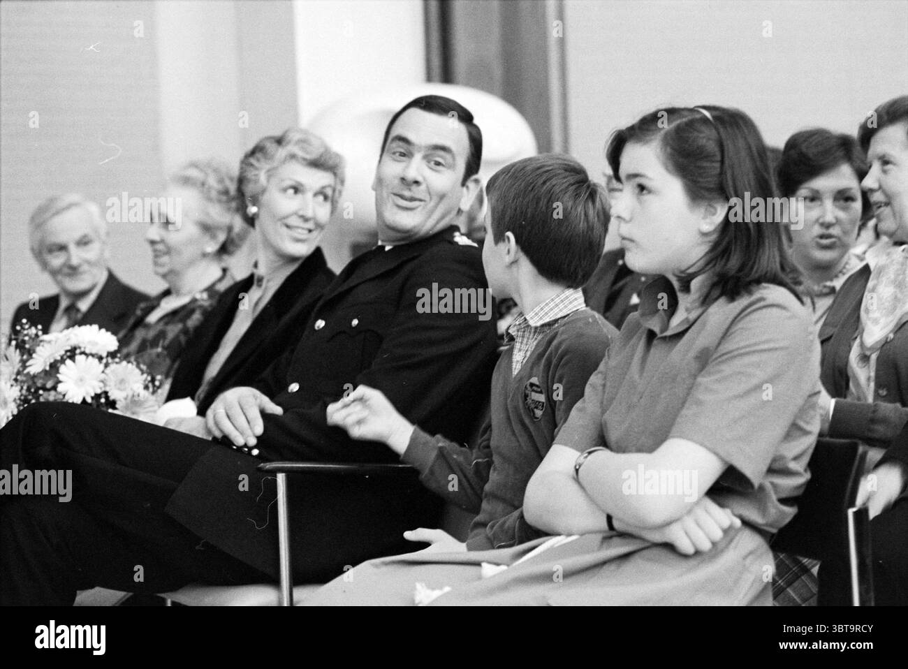 Comm. Installation Miller police, Whizgle News, Dutch Desk, pays-Bas, 1950 - 2000 le 02-05-1980. Voici les rubriques de l'image. Dans un rassemblement, un groupe de personnes est assis étroitement ensemble, créant un sentiment de camaraderie et de communauté. L’espace apparaît bien éclairé, suggérant une atmosphère chaleureuse et accueillante. À gauche, plusieurs femmes âgées avec des cheveux argentés ou gris, affichant un éventail de coiffures, s'assoient avec des expressions allant de l'amusement à l'engagement réfléchi. Leurs vêtements reflètent un mélange de motifs et de couleurs - certains portent des motifs floraux tandis que d'autres optent pour des tons Unis et discrets Banque D'Images