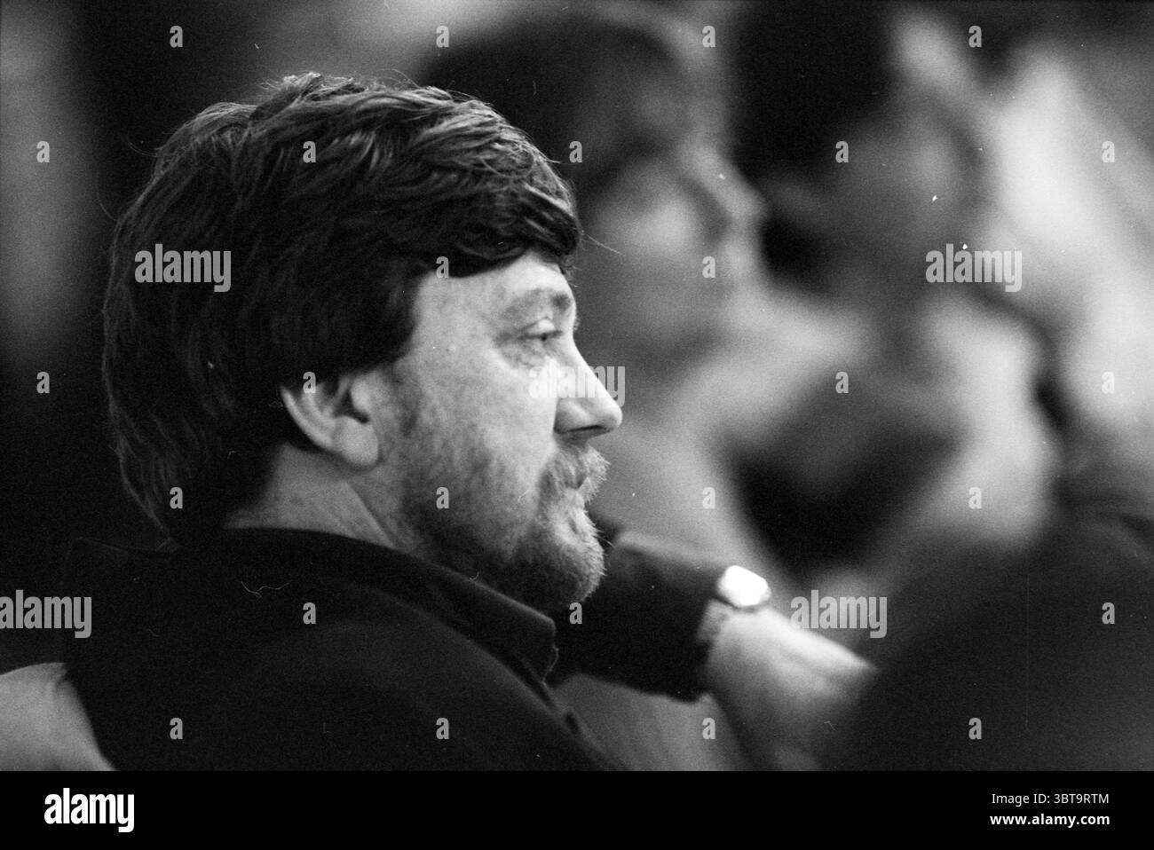 Conseillers budgétaires H'lem Haarlem Grote Markt 2 pays-Bas, Whizgle News, Dutch Desk, pays-Bas, 1950 - 2000 on 03-11-1996. Ces rubriques sont illustrées dans l'image. La scène capture un moment dans un rassemblement, où un homme avec une taille moyenne et une barbe soigneusement taillée est positionné dans le profil. Ses cheveux sont foncés, légèrement émoussés, et il semble être profond dans la pensée, avec une expression contemplative sur son visage. Le cadre est légèrement flou en arrière-plan, suggérant que plusieurs autres personnes sont présentes mais attirant l'attention principalement sur lui. L'éclairage est chaud et légèrement sombre, donnant le Banque D'Images