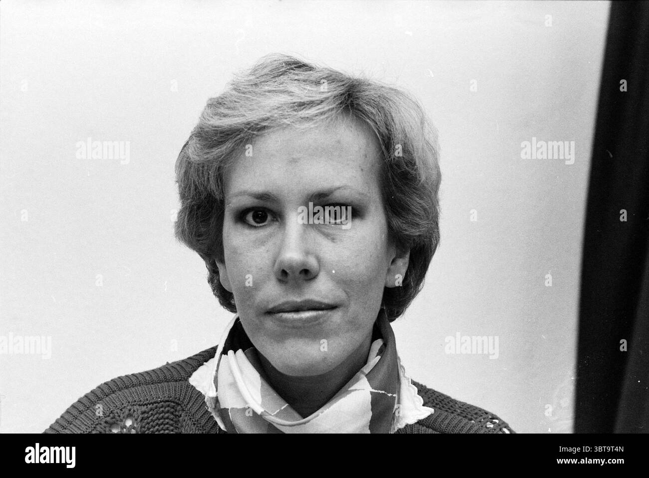 Portrait de MRS Hinke Spier en lien avec Emancipation Portraits Women, Whizgle News, Dutch Desk, pays-Bas, 1950 - 2000 sur 31-03-1983. Ces rubriques apparaissent dans l'image. La scène met en scène une femme, caractérisée par des cheveux courts et clairs coiffés soigneusement. Son expression apparaît contemplative, suggérant un moment d’introspection ou de réflexion. Elle porte un pull qui a un motif texturé, probablement dans une couleur sourde, jumelé avec une écharpe blanche qui ajoute une touche de contraste autour de son cou. L'arrière-plan est simple et discret, probablement un ton léger ou neutre qui le souligne Banque D'Images