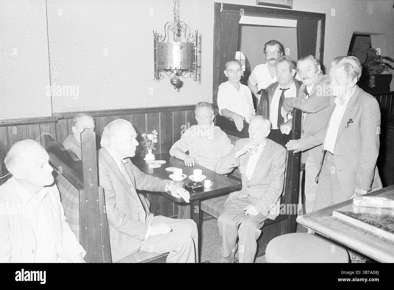 Des hommes qui sont de nouveau sans-abri en raison d'un incendie le 14 octobre 1984 dans la maison d'hôtes Butra (ou : Butro) sur le Hoofdweg à Hoofddorp où ils ont été logés par les services sociaux parce qu'ils étaient sans-abri. Un invité de l'embarquement est mort à la suite de l'incendie. Pompiers. À brûler. Hoofddorp pays-Bas, Whizgle News, Dutch Desk, pays-Bas, 1950 - 2000 on 15-10-1984. Ces rubriques sont illustrées dans l'image. La scène se déroule dans un espace faiblement éclairé et confortable qui respire un sentiment de nostalgie. Des lambris en bois tapissent les murs, contribuant à une atmosphère chaleureuse et accueillante. La lumière émane doucement de vint Banque D'Images