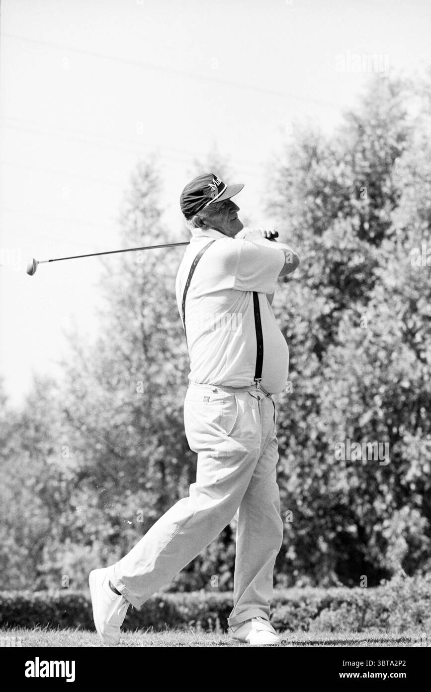 Proam Spaarnwoude Joop Landman, Whizgle News, Dutch Desk, pays-Bas, 1950 - 2000 le 13-08-1993. L'image inclut ces rubriques. Dans un cadre extérieur luxuriant, un golfeur saisit le moment de son swing par une journée ensoleillée. Le golfeur, un homme d'âge moyen, est habillé d'un polo blanc classique et d'un pantalon de couleur claire, dégageant une ambiance détendue mais sportive. Sa tenue est complétée par des bretelles qui ajoutent une touche de style vintage, contrastant avec la casquette de golf moderne perchée sur sa tête. Autour de lui est un paysage vert vibrant parsemé d'herbe soigneusement taillée et d'arbres dispersés, qui Banque D'Images