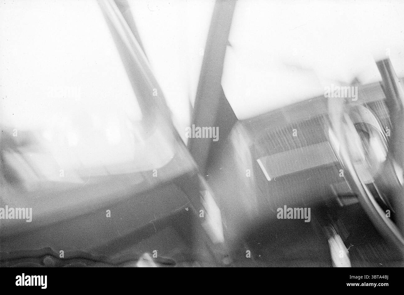 Accident de voiture dû à un empilement dans le brouillard, Whizgle News, Dutch Desk, pays-Bas, 1950 - 2000. L'image contient ces rubriques. La scène présente un espace intérieur flou, probablement celui d’un véhicule, reflétant une atmosphère de mouvement ou d’instabilité. Le cadre est dominé par des tons sombres et sourds, contribuant à une qualité quelque peu abstraite et onirique. Au premier plan, le volant est partiellement visible, avec sa forme circulaire contrastant avec les lignes vives du tableau de bord. La surface du tableau de bord semble texturée, laissant entrevoir une qualité tactile au milieu de la mise au point douce. Li Banque D'Images