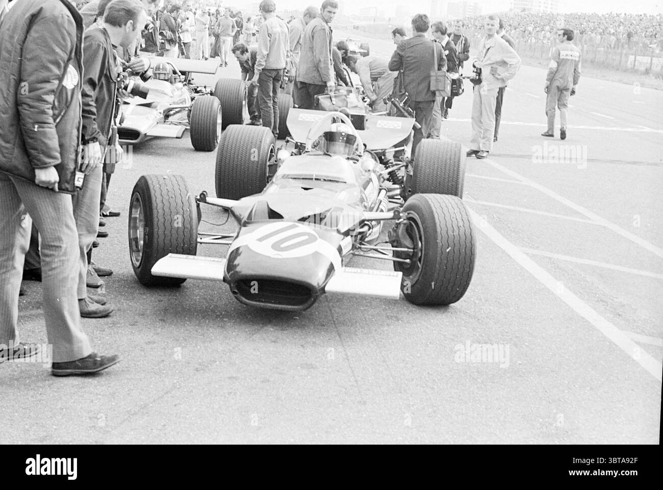 Circuit de course automobile de formule 1 Zandvoort. Zandvoort, Whizgle News, Dutch Desk, pays-Bas, 1950 - 2000 sur 06-1969. Ce sont les éléments de l'image. La scène capture un paddock animé de sports motorisés, vivant avec de l'activité alors que les participants se préparent pour une course. Au premier plan, une voiture de course élégante arborant le numéro « 10 » sur sa carrosserie domine. La conception de la voiture est aérodynamiquement lisse, avec un nez allongé et des pneus larges, suggérant vitesse et puissance. La palette de couleurs présente une combinaison de tons sombres, probablement en contraste avec les couleurs vives de l'atmosphère environnante. Po Banque D'Images