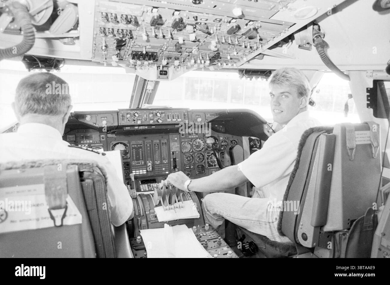 E. Jongejans at Schiphol + parking M. Schroder parking parkings parkings Schiphol Schiphol, Whizgle News, Dutch Desk, pays-Bas, 1950 - 2000 on 01-09-1989. L'image montre ces rubriques. La scène montre le cockpit d'un avion, où deux individus sont positionnés. La première personne, assise à gauche, est concentrée sur la gamme de commandes et d'instruments devant lui. Sa tenue est élégante et décontractée, probablement une chemise blanche qui contraste avec les éléments plus sombres du cockpit. Le cockpit lui-même est rempli d'un mélange complexe de cadrans, de boutons et d'écrans, tous dans divers algues Banque D'Images