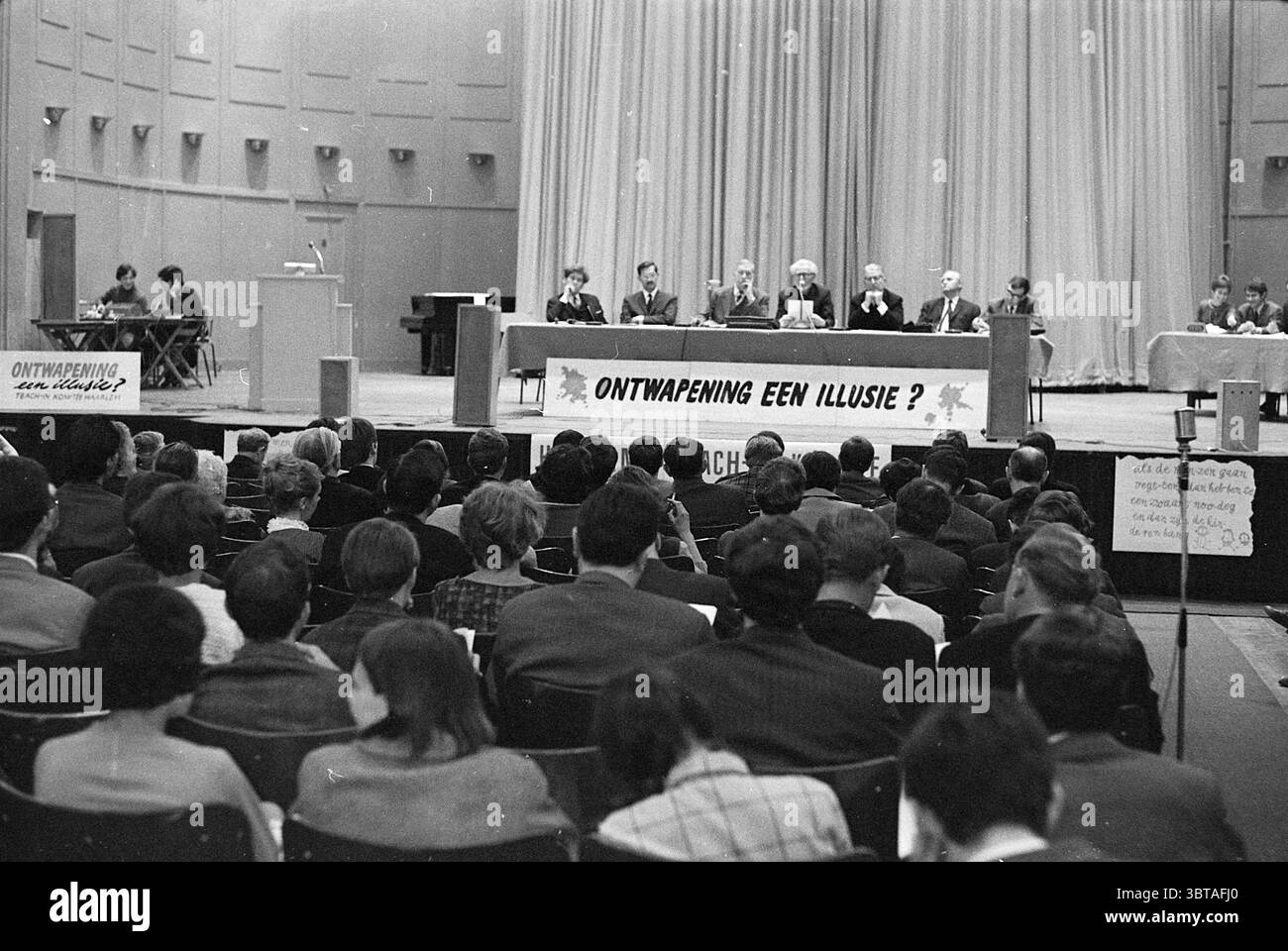 Réunions d'enseignement sur le désarmement, Whizgle News, Dutch Desk, pays-Bas, 1950 - 2000 on 11-05-1968. L'image inclut ces rubriques. La scène se déroule dans un grand auditorium intérieur caractérisé par son espace et ses hauts plafonds. Au premier plan, un panneau de cinq personnes est assis derrière une longue table, qui est ornée de plusieurs objets, peut-être des microphones et des verres à eau, le tout de manière propre et organisée. Les individus sont habillés en tenue professionnelle, véhiculant une atmosphère formelle et sérieuse. Derrière eux, un grand rideau de scène est suspendu, son tissu doux drapant en douceur, des sucres Banque D'Images