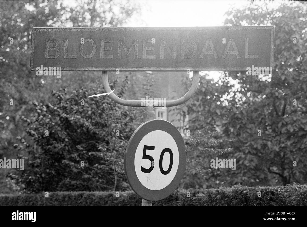 Signe Bloemendaal et Heemstede, Whizgle News, Dutch Desk, pays-Bas, 1950 - 2000 le 25-09-1994. L'image inclut ces rubriques. La scène présente un panneau de signalisation altéré à une intersection, suggérant qu'il marque un emplacement ou un point d'intérêt. Le signe lui-même a un aspect rustique et vieilli, indiquant qu'il a été exposé aux éléments au fil du temps. Le lettrage est légèrement délavé et usé, contribuant à un sentiment général de nostalgie ou d'histoire. Niché en arrière-plan, un assortiment luxuriant de verdure encadre le signe, avec diverses nuances de riches feuilles vertes et peut-être quelques notes de Banque D'Images