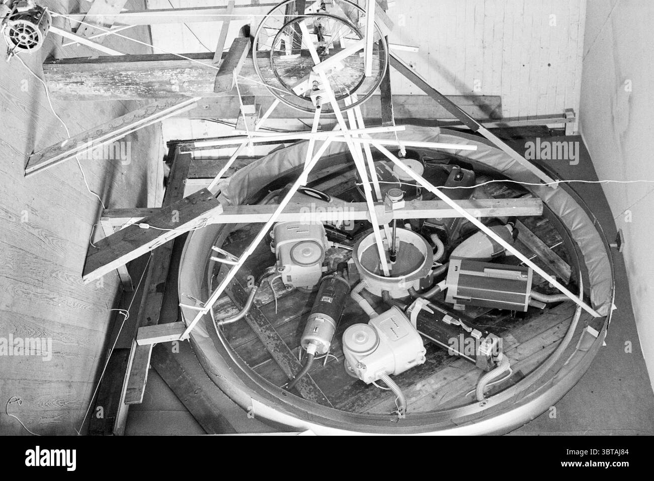 Stone Fountain' vide Cultura, Whizgle News, Dutch Desk, pays-Bas, 1950 - 2000 on 17-04-1995. Ces rubriques apparaissent dans l'image. La scène présente un cadre industriel caractérisé par un arrangement complexe de machines et d'éléments structurels. Dominant le centre est une plate-forme circulaire qui semble supporter plusieurs moteurs et composants mécaniques, mettant en valeur un design complexe. La machinerie est composée de divers tons métalliques, avec des nuances d'argent et de gris, présentant un contraste frappant sur l'arrière-plan plus clair. Au-dessus de l'assemblage circulaire, des poutres de bois croisées, des sucres Banque D'Images